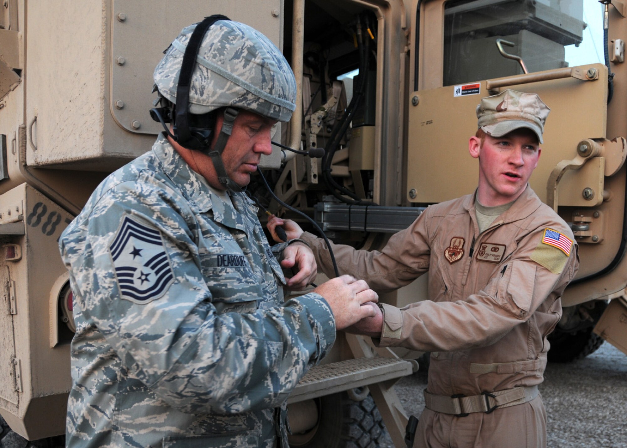CAMP BUCCA, IRAQ -- Airman 1st Class Phillip Brooks, 887th Expeditionary Security Forces Squadron, assists 9th Air Force Command Chief Master Sgt. Scott Dearduff ,  with the proper way to attach hearing protection before departing on a convoy from Camp Bucca, Iraq, April 4. During his visit to the Area of Responsibility, Command Chief Dearduff introduced the new tactical uniforms for Airmen working outside the wire. Airman Brooks is currently deployed from Moody Air Force Base, Ga. (U.S. Air Force photo/ Senior Airman Courtney Richardson)