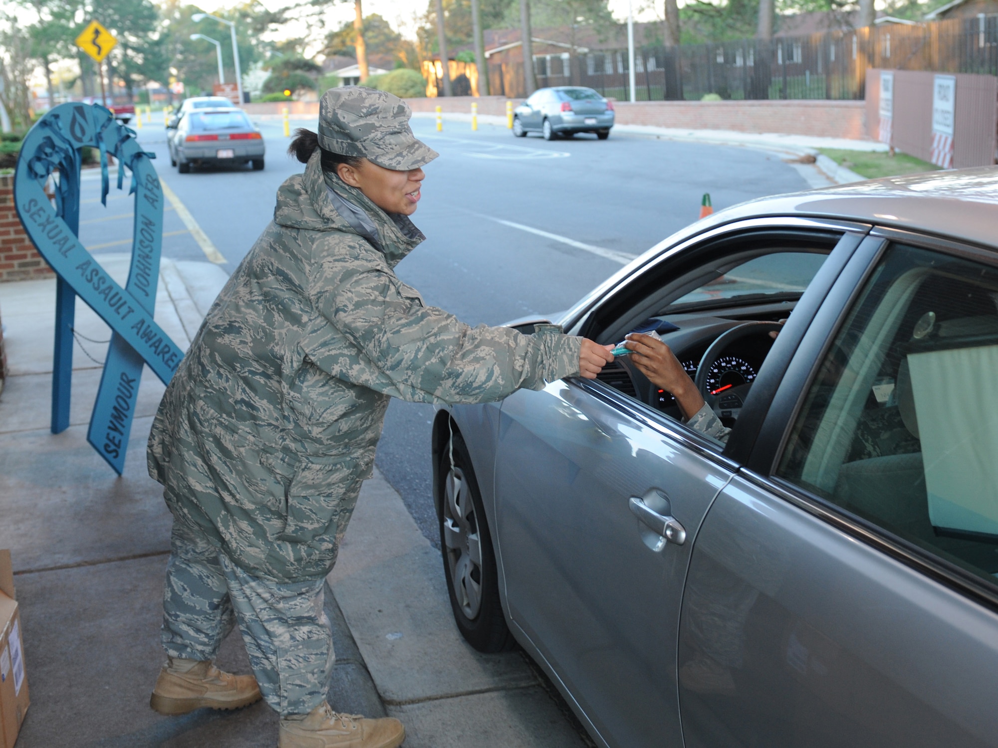 Staff Sgt. Natasha Curry, 4th Force Support Squadron, passes a flashlight to an Airman at the Berkley Gate on Seymour Johnson Air Force Base, N.C., April 8. 2009. April is Sexual Assault Awareness Month and April 8th specifically is the national day of action. The Sexual Assault Prevention and Response office distributes information with pamphlets, water bottles, clips and key chains. (U.S. Air Force photo by Airman 1st Class Whitney Lambert) 