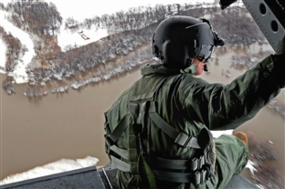 U.S. Army Staff Sgt. Jon Scarber, a flight engineer, looks out over the flooded Red River along the North Dakota-Minnesota border from a CH-47D Chinook helicopter, April 1, 2009. The Montana Army National Guard is assisting flood relief efforts around Grand Forks, N.D., and is conducting flights to familiarize aviators and soldiers with possible hazards in the region. The soldiers are assigned to the 1st Battalion, 189th Aviation Regiment.