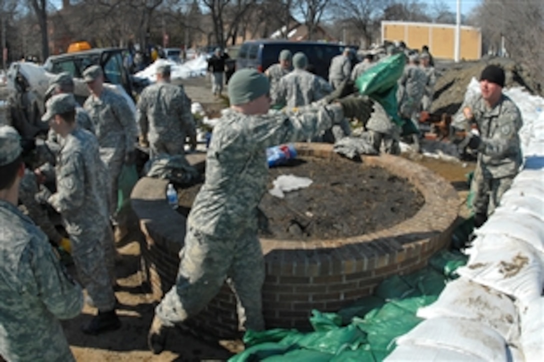 U.S. Army Spc. Ryan Lindberg, center, a member of the North Dakota National Guard's 817th Engineer Company, tosses a sandbag from one soldier to another in Valley City, N.D., April 8, 2009. The soldiers are positioning the sandbags to create a temporary levee along the rising flood water of the Sheyenne River. 
