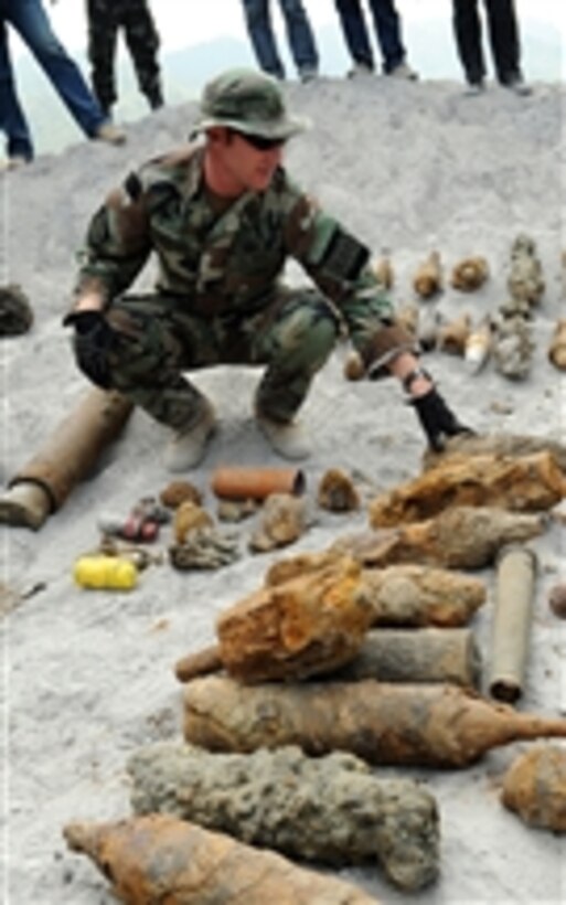U.S. Navy Chief Petty Officer Kenneth Simpson, assigned to Joint Special Operations Task Force-Philippines Explosive Ordnance Disposal Task Unit, inspects ordnance before its scheduled disposal at Crow Valley, Philippines, as members of Philippine security forces listen in on March 25, 2009.  The U.S. Explosive Ordnance Disposal Task Unit assists Philippine security forces by offering their counterparts technical assistance and information sharing.  