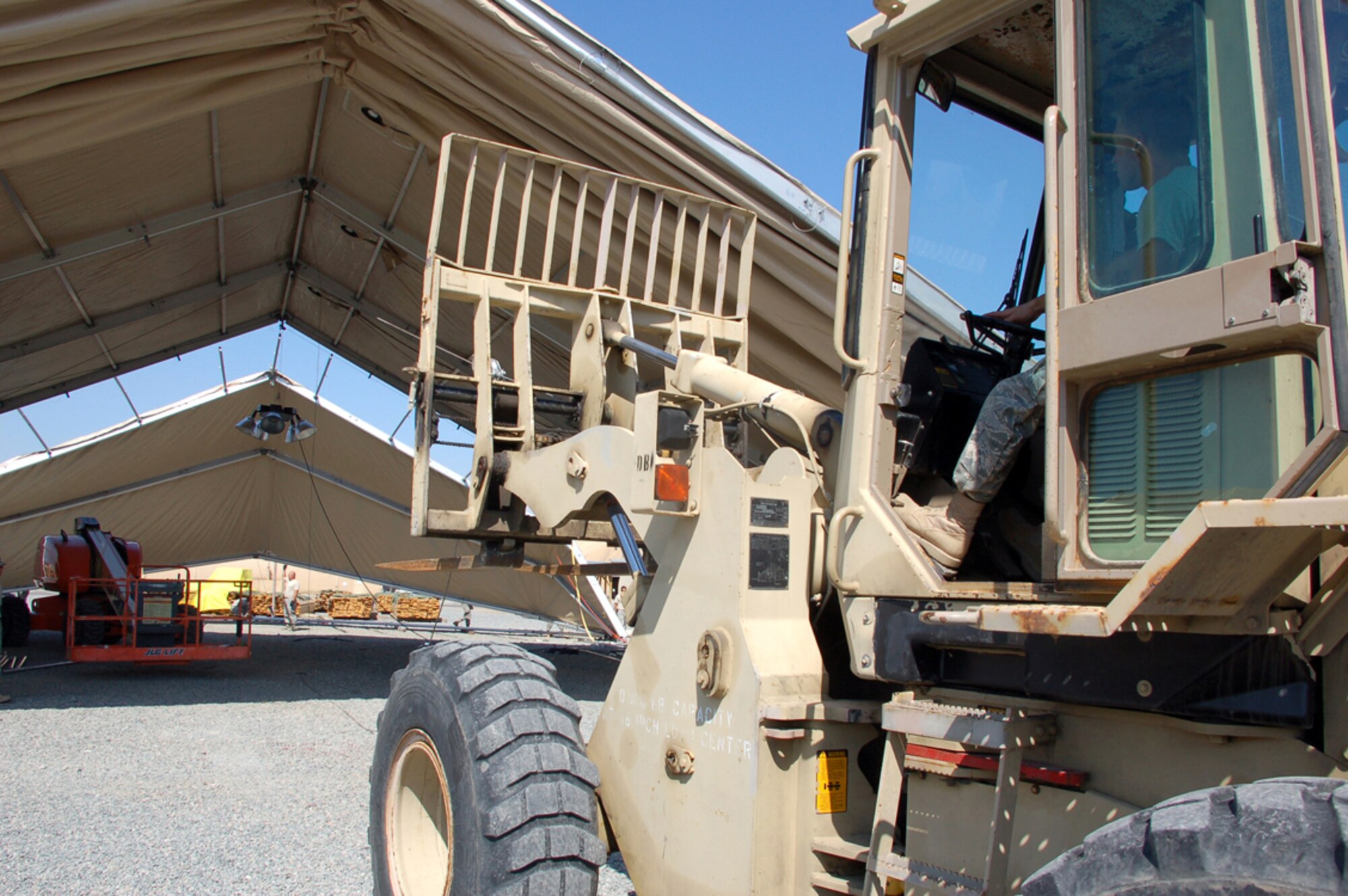 Senior Airman Brian Luft backs up a forklift attached to a cable pulling together two sections of a 4,000-square foot dome shelter under construction April 1 at Manas Air Base, Kyrgyzstan. The tents are being erected in preparation for the increased number of coalition personnel transiting through Manas AB to and from Afghanistan. Airman Luft is assigned to a nine-person Basic Expeditionary Airfield Resources team deployed to Southwest Asia. He is deployed from Holloman Air Force Base, N.M., and originally from St. Marys, Md. (U.S. Air Force photo/Tech. Sgt. Phyllis Hanson) 
