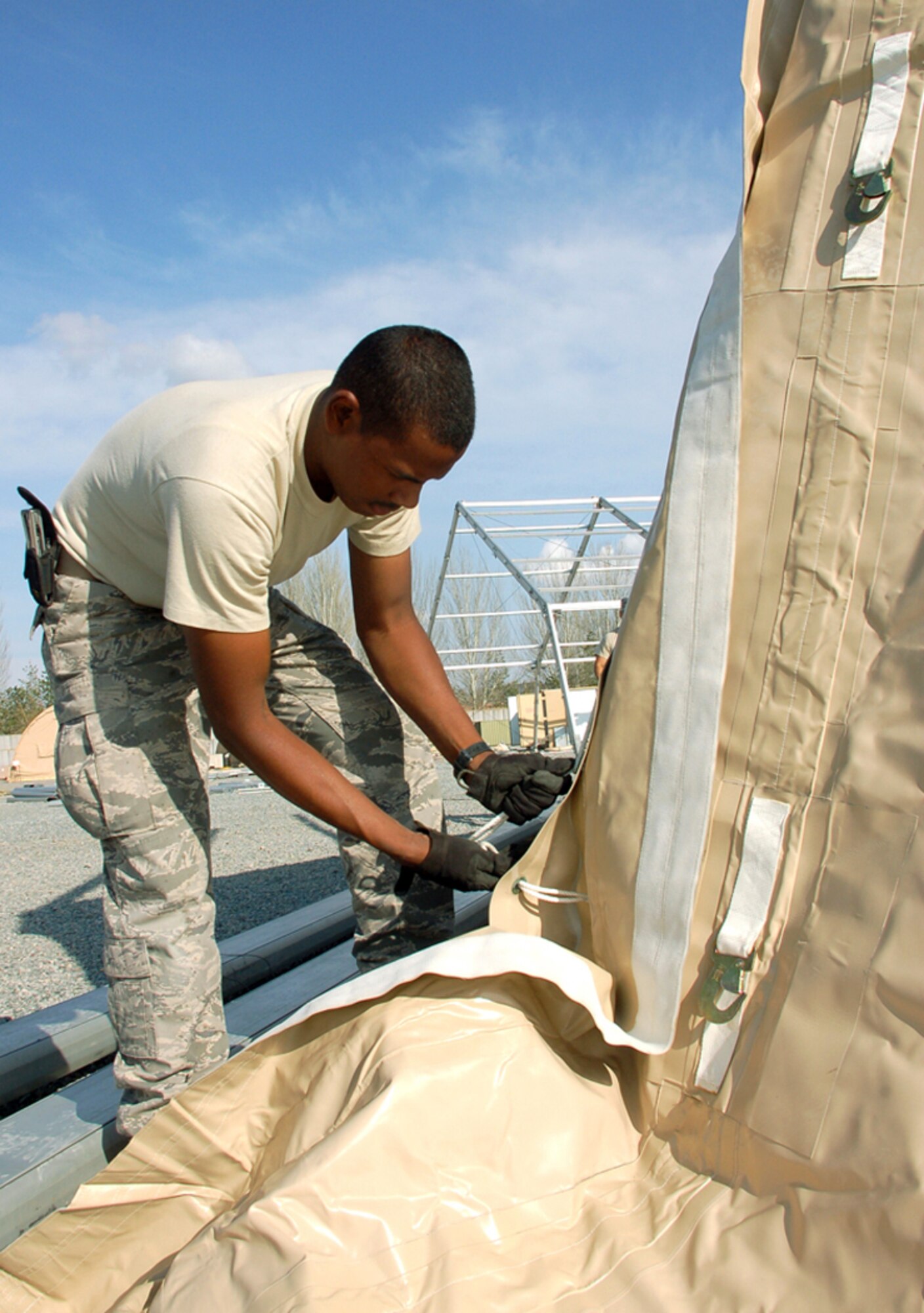 Staff Sgt. Timothy Robinson laces together the front panels of a 4,000-square-foot dome shelter being built March 30 at Manas Air Base, Kyrgyzstan. The tents are being erected in preparation for the increased number of coalition personnel transiting through Manas to and from Afghanistan. Sergeant Robinson is assigned to a nine-person Basic Expeditionary Airfield Resources team deployed to Southwest Asia. He is deployed from Holloman Air Force Base, N.M. (U.S. Air Force photo/Tech. Sgt. Phyllis Hanson) 
