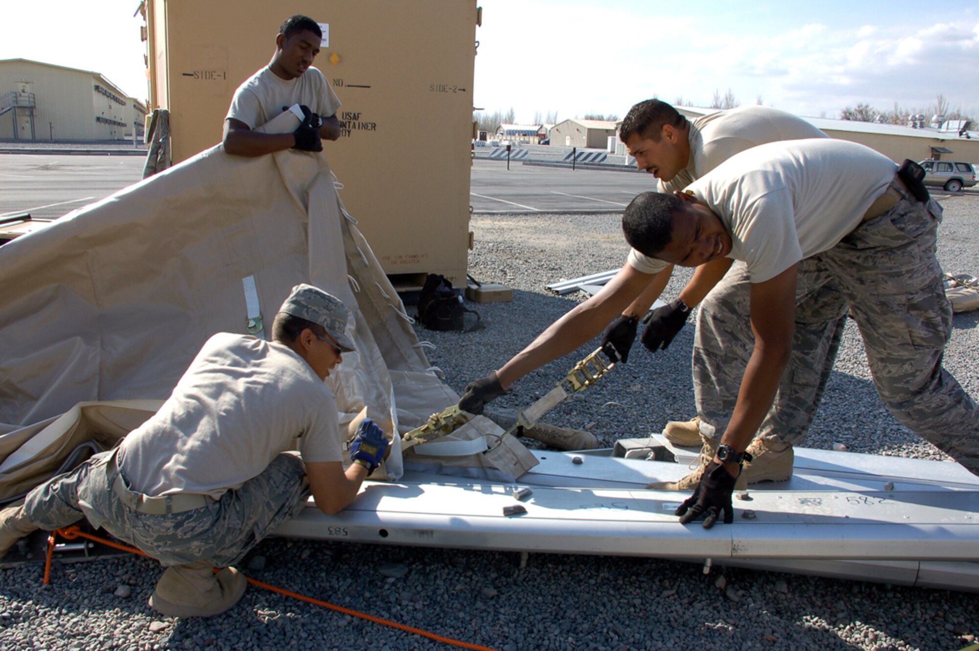 Airman 1st Class Jonathan Candelaria (from left to right), Airman 1st Class Keeon Pullen, Staff Sgt. Timothy Robinson and Staff Sgt. Eric Lopez pull vinyl-composite material through the slots of in-wall arches during the construction of a 4,000-foot dome, being built March 30 at Manas Air Base, Kyrgyzstan. The tents are being erected in preparation for the increased number of coalition personnel transiting through Manas to and from Afghanistan. The Basic Expeditionary Airfield Resources team are deployed from Holloman Air Force Base, N.M. (U.S. Air Force photo/Tech. Sgt. Phyllis Hanson) 
