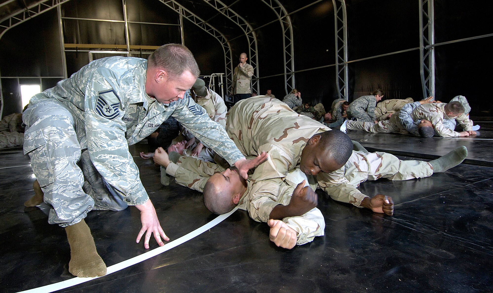 During a hand-to-hand combat class, Master Sgt. Bryan Kaut, Combat Readiness School instructor, gives pointers to 33rd Combat Communications Squadron members, Airman Dallas Gilbertson, pinned, and Airman 1st Class Jeff Alexandre.  (Air Force photo/Margo Wright)