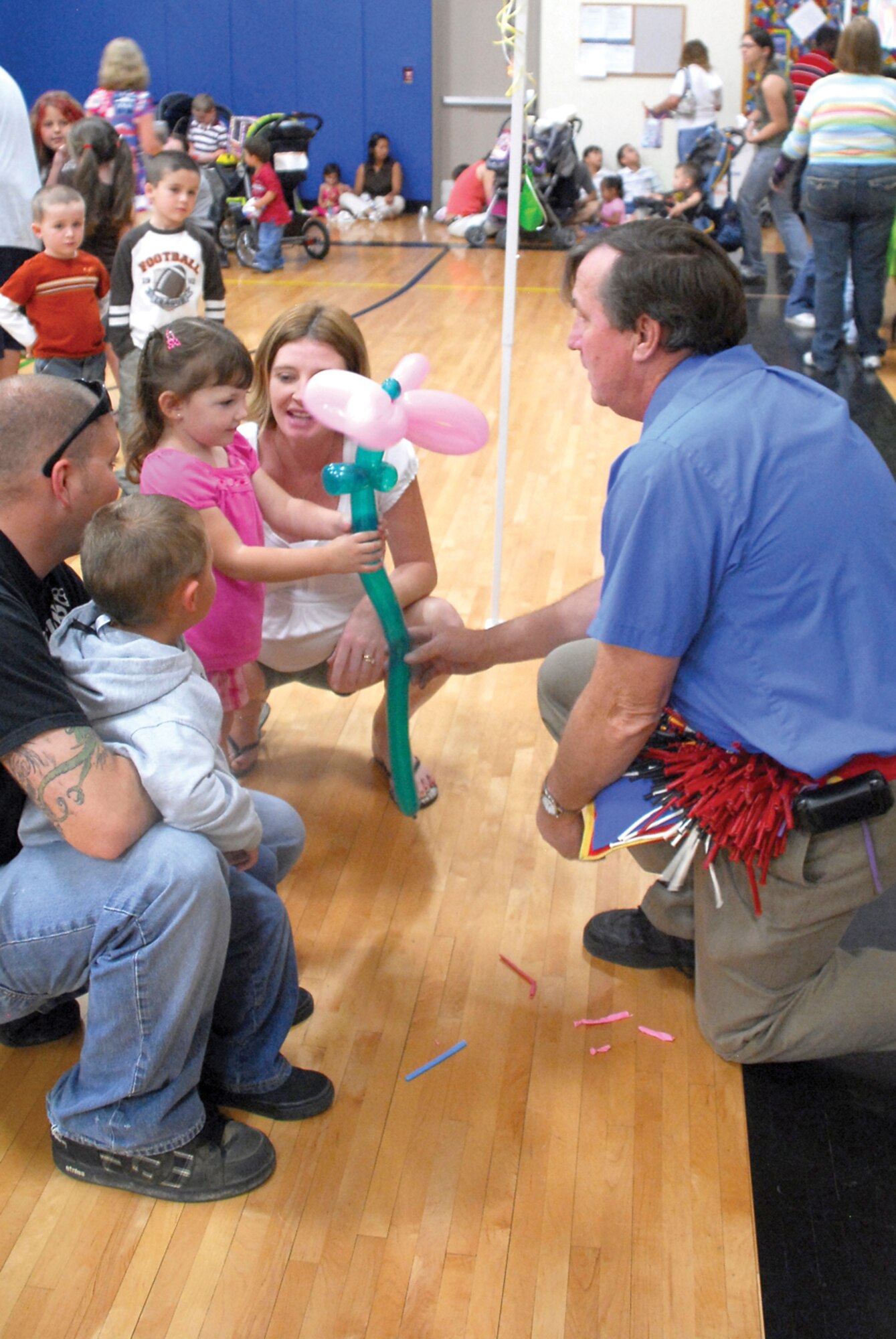 Kaiya Morton, 3, receives a flower, made of balloons, from Joe Goodwin during the Luke Air Force Base “Eggstravaganza.” (U.S. Air Force photo/ Airman 1st Class Tracie Forte)