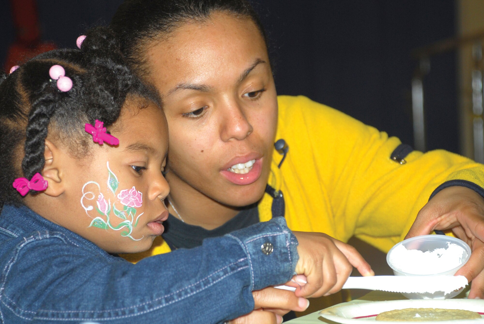 Regina Robertson, 3, and her mother, Staff Sgt. Regina Robertson from the 56th Logistics Readiness Squadron, frost a cookie in the cookie decorating booth of the Luke Air Force Base “Eggstravaganza” at the youth center, April 3. (U.S. Air Force photo/ Airman 1st Class Tracie Forte)