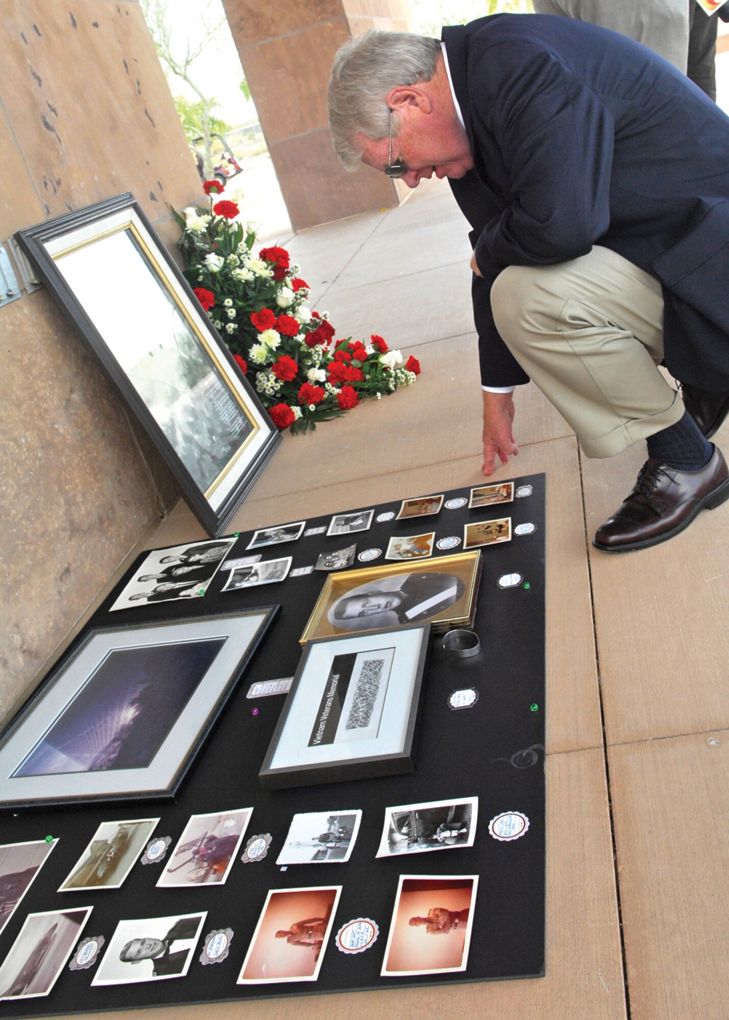 An attendee of the funeral service for Lt. Col Earl P. Hopper looks over pictures from his childhood after the ceremony April 3 at the National Memorial Cemetery of Arizona in Phoenix. (U.S. Air Force photo/Photos by Tech. Sgt. Raheem Moore)