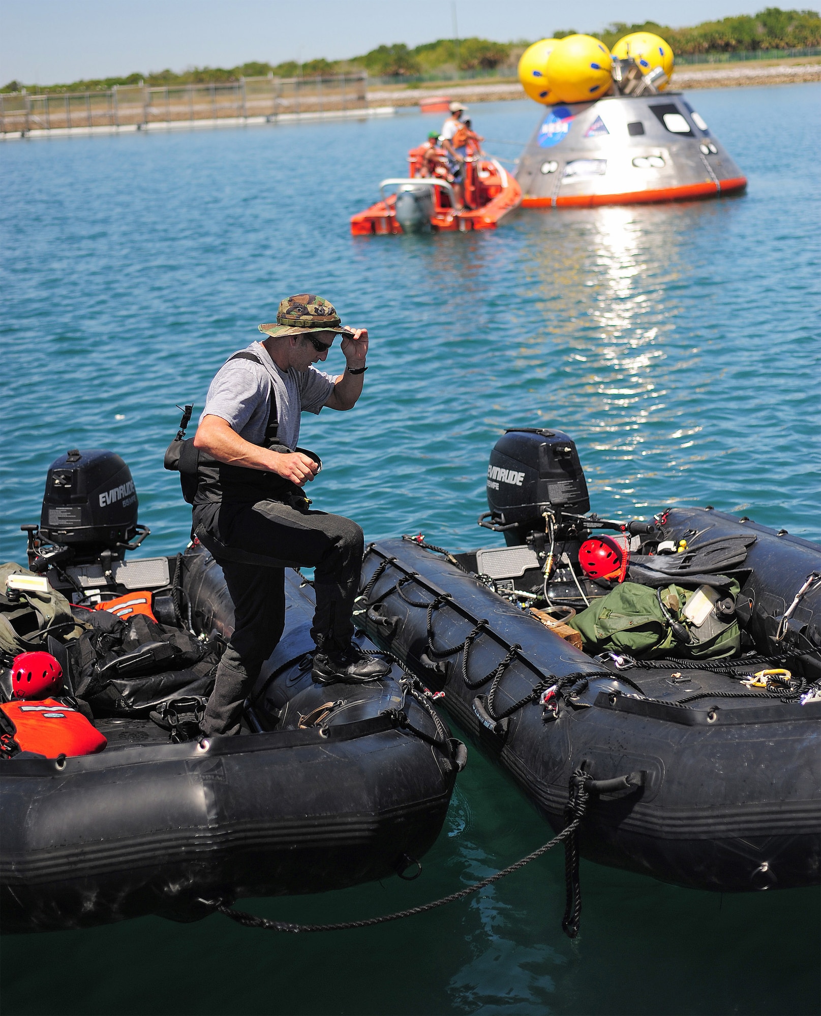 Master Sgt. Chris Seinkner uses a pair of inflatable Zodiac boats as a bridge back to dry land after testing a mockup of the Orion crew exploration vehicle (seen in the background) March 8 at the Trident Basin at Port Canaveral, Fla. Sergeant Seinkner was part of a six-man team of pararescuemen testing an inflatable flotation collar. The collar is designed both to stabilize the capsule after water landing and provide a platform for recovery personnel to stand on during the operation. Sergeant Seinkner is a pararescueman from the Air Force Reserve's 920th Rescue Wing. (U.S. Air Force photo/Tech. Sgt. Paul Flipse) 
