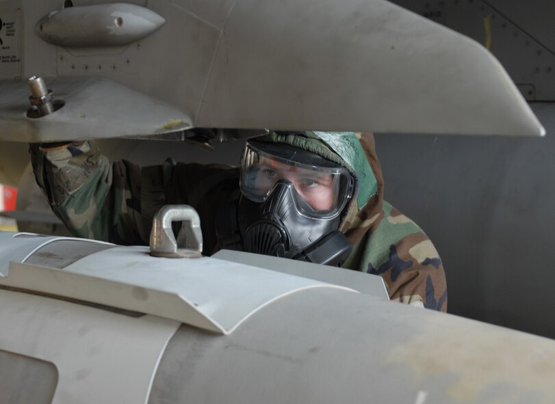 Staff Sgt. Stephen Dugas, 8th Aircraft Maintenance Squadron, helps load a bomb during a monthly Weapons Load Competition at Kunsan Air Base, Republic of Korea, April 10. Airmen participated in load competition while wearing chemical protection gear in preparation for the upcoming Operational Readiness Inspection. (U.S. Air Force Photo/Senior Airman Gustavo Gonzalez)