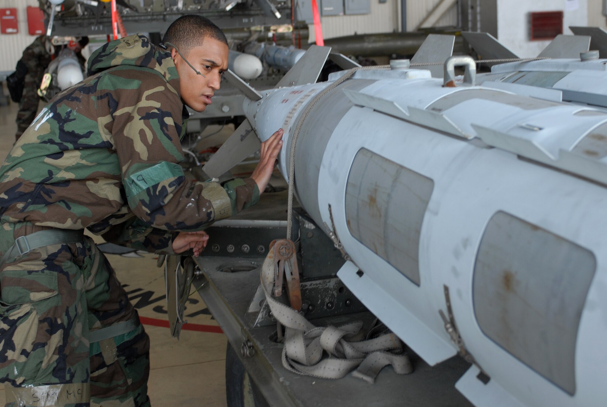 Staff Sgt. Shaun-Ryan Batson, 8th Aircraft Maintenance Squadron, unstraps a bomb in preperation for loading during the monthly Weapons Load Competition at Kunsan Air Base, Republic of Korea, April 10. Airmen participated in load competition while wearing chemical protection gear in preparation for the upcoming Operational Readiness Inspection. (U.S. Air Force Photo/Senior Airman Gustavo Gonzalez)