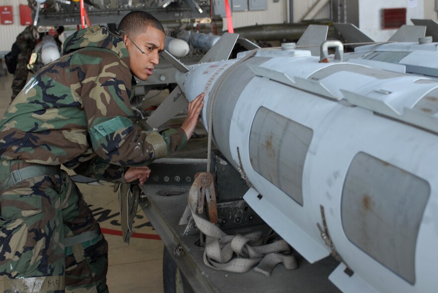 Staff Sgt. Shaun-Ryan Batson, 8th Aircraft Maintenance Squadron, unstraps a bomb in preperation for loading during the monthly Weapons Load Competition at Kunsan Air Base, Republic of Korea, April 10. Airmen participated in load competition while wearing chemical protection gear in preparation for the upcoming Operational Readiness Inspection. (U.S. Air Force Photo/Senior Airman Gustavo Gonzalez)