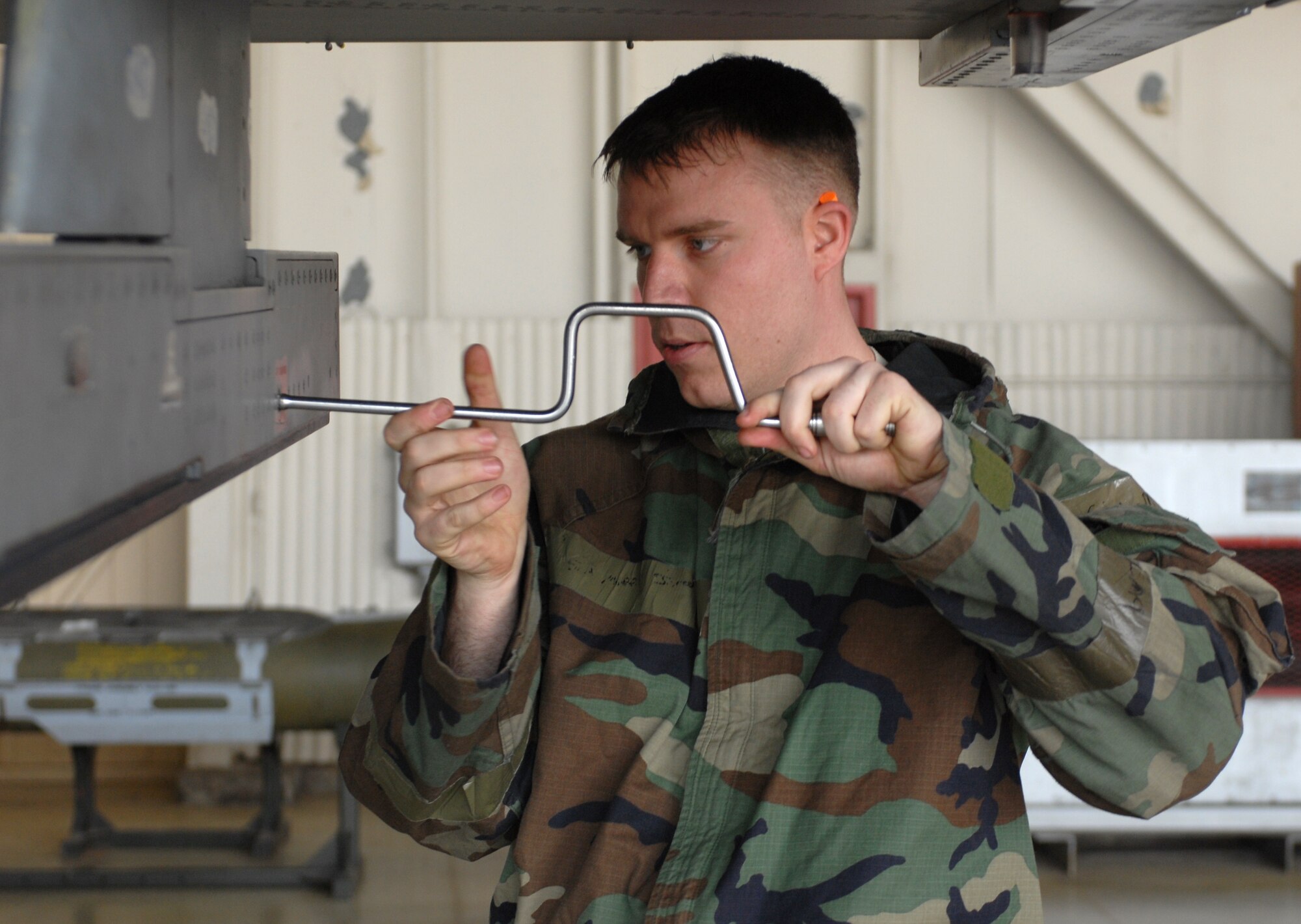 Senior Airman Jarod Moffit, 8th Aircraft Maintenance Squadron, uses a speed handle to open a panel in preparation for bomb loading during the monthly Weapons Load Competition at Kunsan Air Base, Republic of Korea, April 10. Airmen participated in load competition while wearing chemical protection gear in preperation for the upcoming Operational Readiness Inspection. (U.S. Air Force Photo/Senior Airman Gustavo Gonzalez)