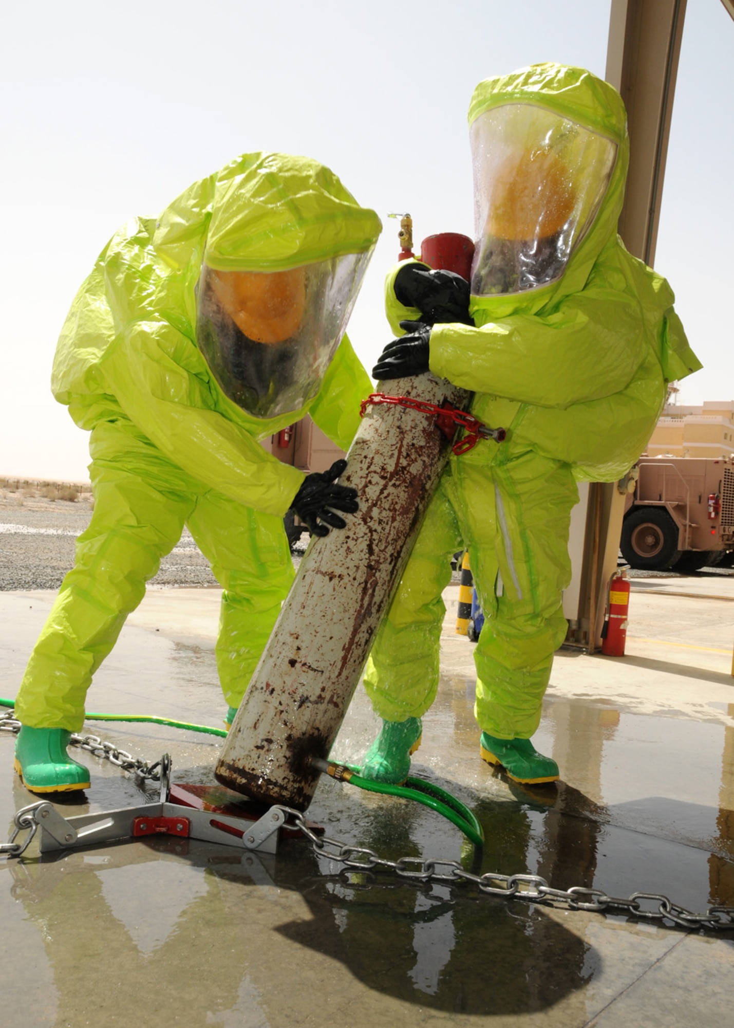 SOUTHWEST ASIA -- HazMat technician students use teamwork to move a simulated gas cylinder into place to apply chains to the cap in order to contain a leak during Hazardous Material training at an air base in Southwest Asia, April 9. The students are required to complete an academic training and hands-on instruction to mitigate potential Hazardous Materials incidents. (U.S. Air Force photo/ Senior Airman Courtney Richardson)