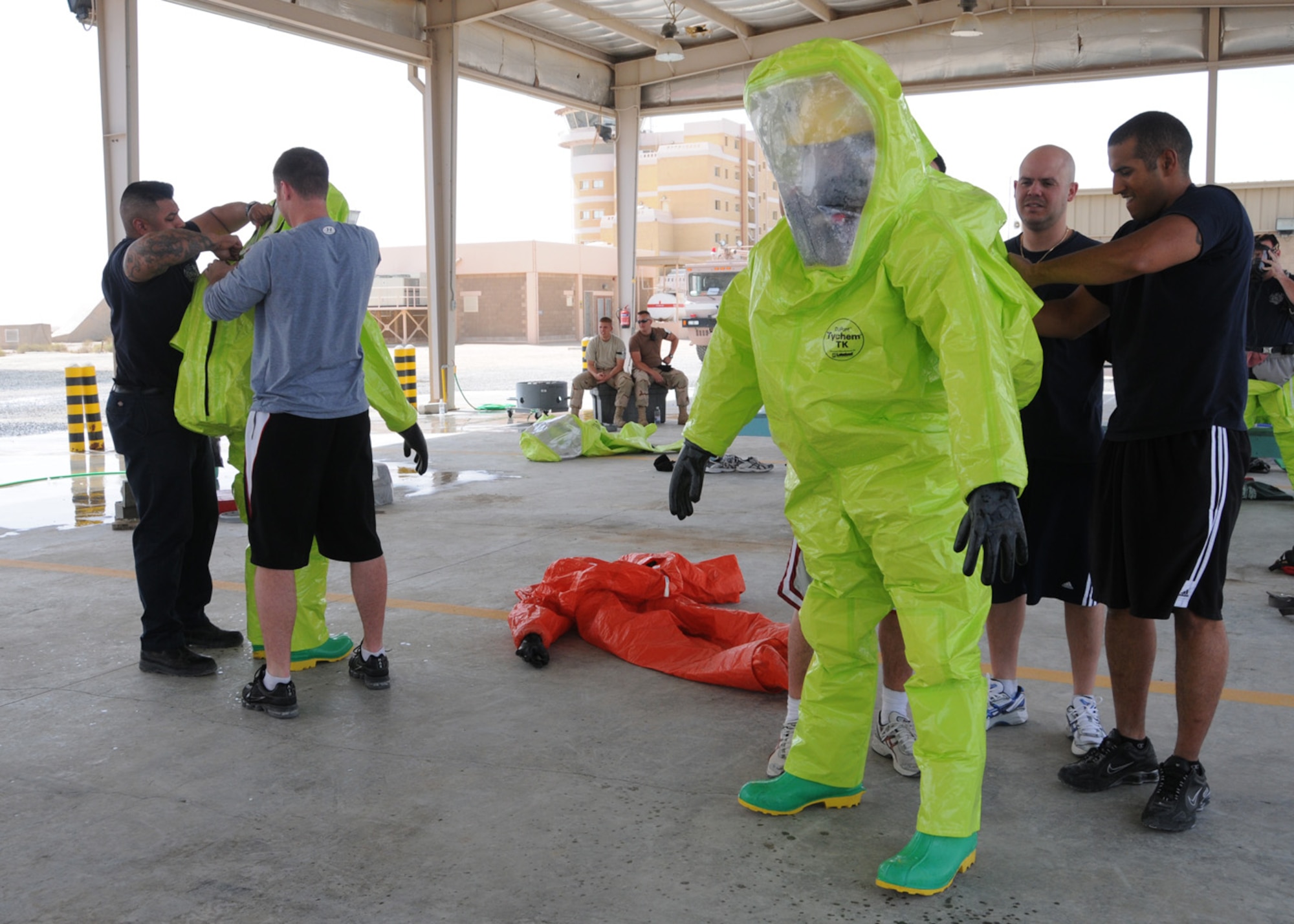 SOUTHWEST ASIA -- Military personnel use the buddy system to get dressed in a Level A Fully Encapsulated Hazardous Materials suit during Hazardous Materials training at an air base in Southwest Asia, April 9. The training included Airmen firefighters, Soldiers and civilian contract firefighters, and other Emergency Services. (U.S. Air Force photo/ Senior Airman Courtney Richardson)