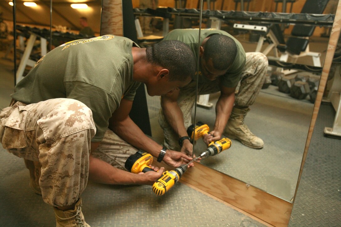Staff Sgt. Trent Nichols, a section leader with Regimental Combat Tem 8’s Mobile Security Detachment, installs a mirror in the newly refurbished Camp Ripper gym, April 11, 2009.  The facility now has new mirrors, flooring and front desk area.