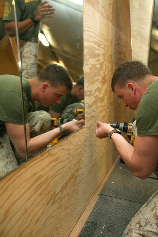 Lance Cpl. Seth Haut, a motor transportation operator with Regimental Combat Team 8’s Mobile Security Detachment, attaches a new mounting bracket to the wall of the refurbished Camp Ripper gym, April 11, 2009.  The new mirrors are just a few new additions to the gym including a new floor and front desk area.