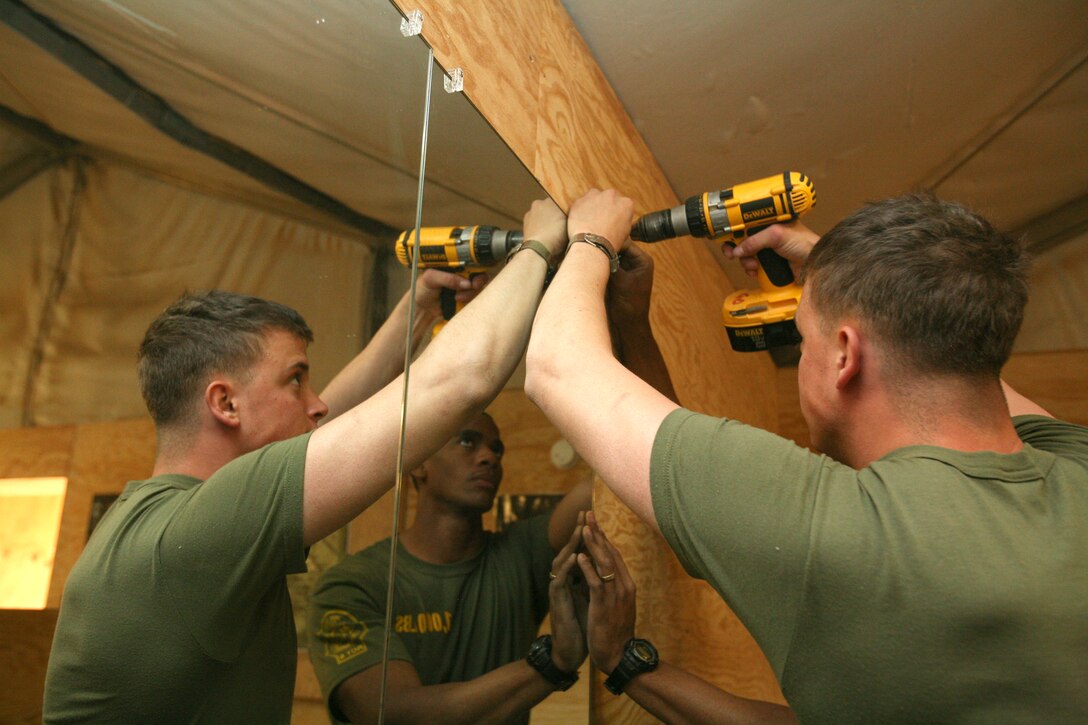 Lance Cpl. Seth Haut, a motor transportation operator with Regimental Combat Team 8’s Mobile Security Detachment, attaches a new mounting bracket to the wall of the refurbished Camp Ripper gym, April 11, 2009.  The new mirrors are just a few new additions to the gym including a new floor and front desk area.