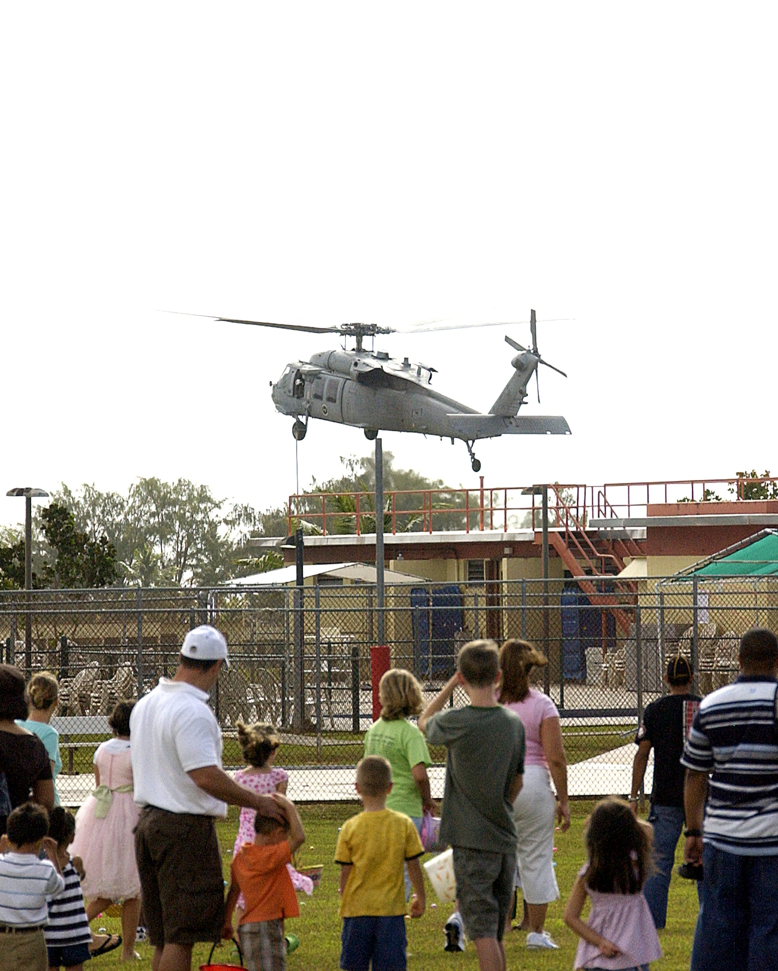 ANDERSEN AIR FORCE BASE, Guam -- Team Andersen members lined up for the Easter egg hunt watch an MH-60S Knighthawk land during the Spring Carnival held on youth center grounds April 11. Approximately 600 Team Andersen personnel attended this event. (U.S. Air Force photo by Airman Carissa Wolff)           