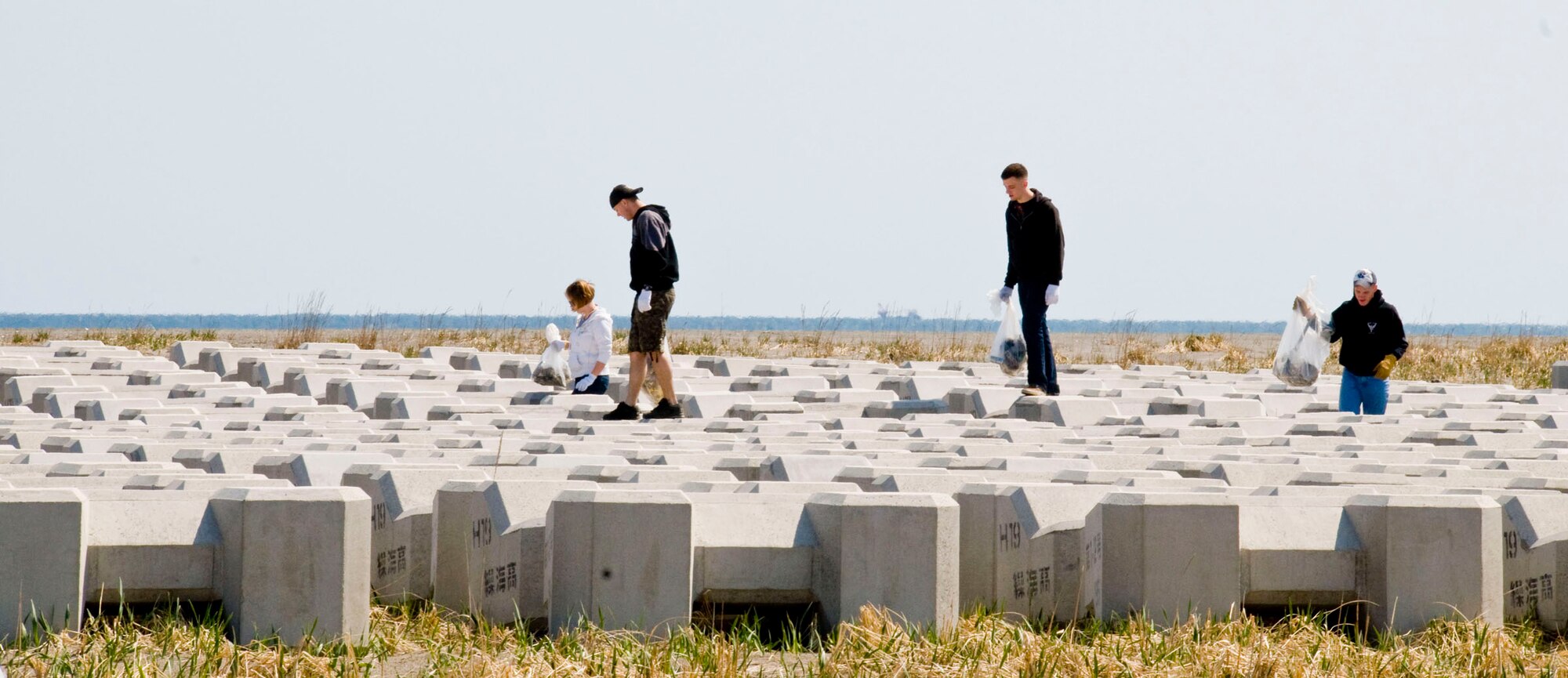 MISAWA, Japan -- Misawa Air Base personnel look for trash between concrete barriers at the Misawa port April 11, 2009. The annual beach and port cleanup helps educate people on the importance of keeping the environment clean. (U.S Air Force photo by Staff Sgt. Araceli Alarcon)