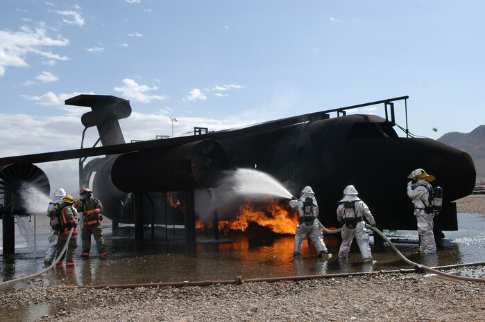 A firefighter crew from Clark County Fire Department assigned to McCarran International Airport hose down a fire outside of an aircraft mockup as part of the required Federal Aviation Administration training, held at Nellis Air Force Base, Nev., April 3. The three-day training hosted 33 firemen from the Clark County Fire Department. (U.S. Air Force photo by Staff Sgt. Aileen Carter)