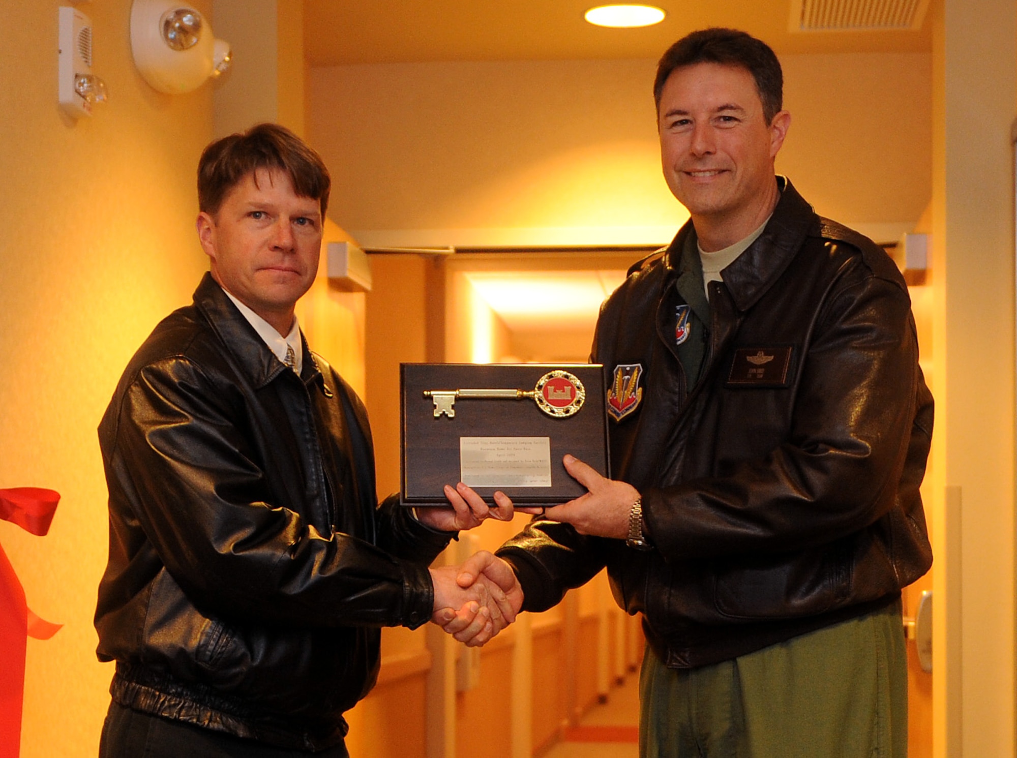 MOUNTAIN HOME AIR FORCE BASE, Idaho – Col. John Bird II, 366th Fighter Wing commander, receives the “key” to the new temporary living facility from Drasa Maciunas, Army Corps of Engineer, Seattle District, during a ribbon-cutting ceremony April 10 in the main lobby entrance. This facility more than doubles the old capabilities of the facility to care for in-transit personnel and their dependents and includes 20 two-bedroom units and 15 one-bedroom units -- including pet friendly and American Disabilities Act compliant rooms. (U.S Air Force photo\ Airman 1st Class Deborah Lockhart)