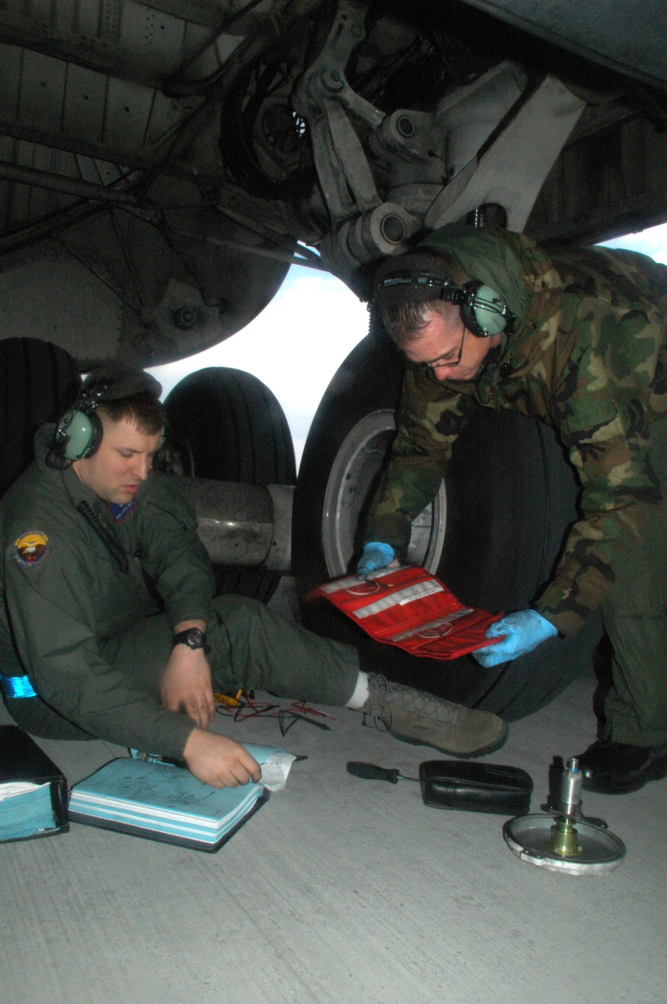 Staff Sgt. Aaron Trudel (left) and Staff Sgt. Ryan Carver, 436th Airlift Wing and C-5M flying crew chiefs, refer to technical orders to repair brakes on the aircraft during its first official mission, March 28 to April 9. The C-5M crew consisted of members from 512th and 436th Airlfit Wings and Lockheed Martin field service representatives. The aircrew made stops at McGuire Air Force Base, N.J., Ramstein Air Base, Germany, and Gander International Airport, Canada. (U.S. Air Force photo/Senior Airman Andria J. Allmond) 