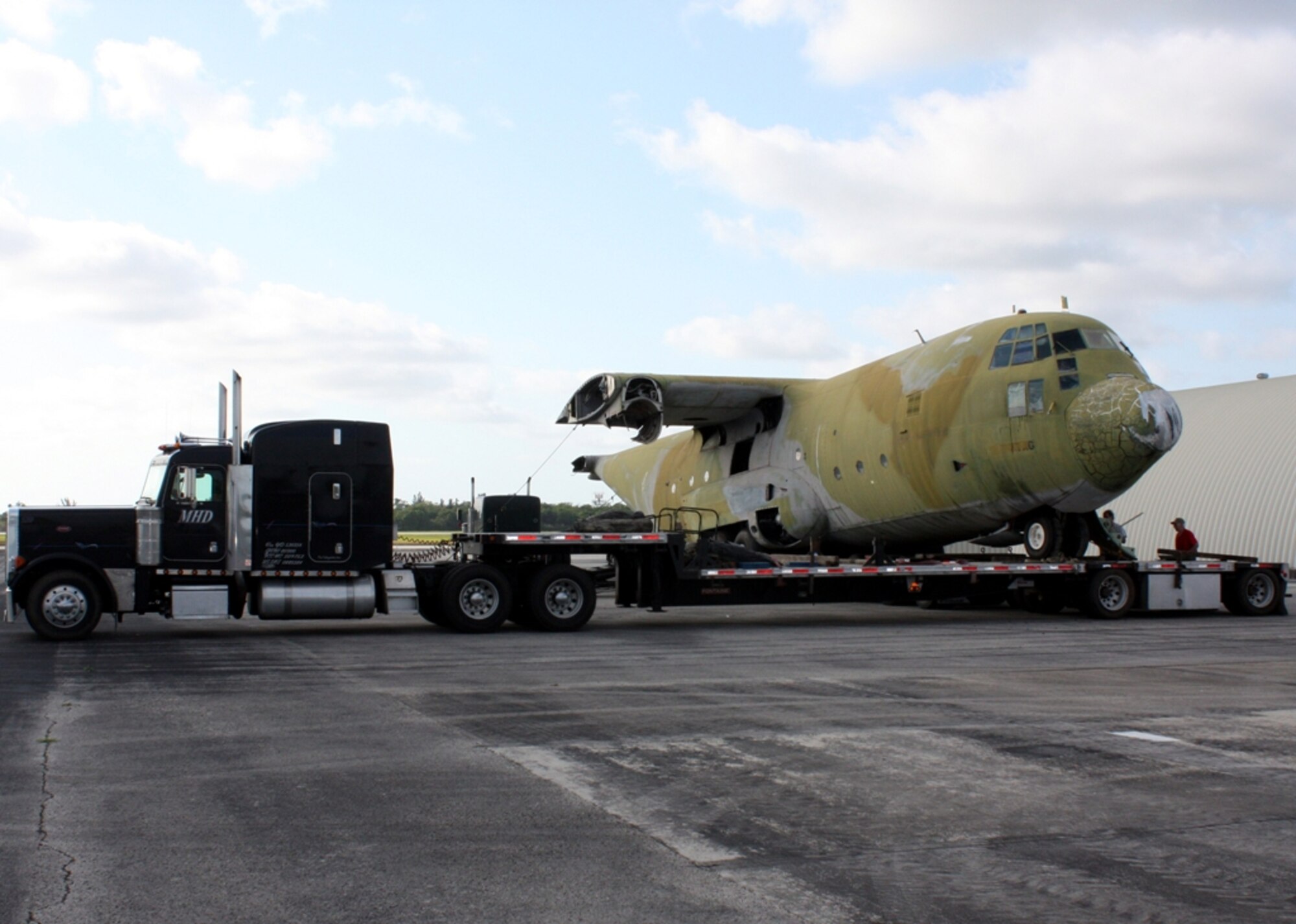 HOMESTEAD AIR RESERVE BASE, Fla. – Contractors load the remains of a C-130 transport aircraft onto a truck for removal from the end of the flightline on April 1. What was left of the wings was sawed off, and the 56,000-pound hulk will be driven to recycling plant where the aluminum will be smelted down and reused. The C-130 remains have long been a fixture on base. It was damaged beyond repair during Hurricane Andrew in 1992, and was subsequently used for training by the 70th Aerial Port Squadron for many years. The aircraft was one of Lockheed Martin’s original C-130 “A” models produced in 1956. (U.S. Air Force photo/2nd Lt. Erik Hofmeyer)