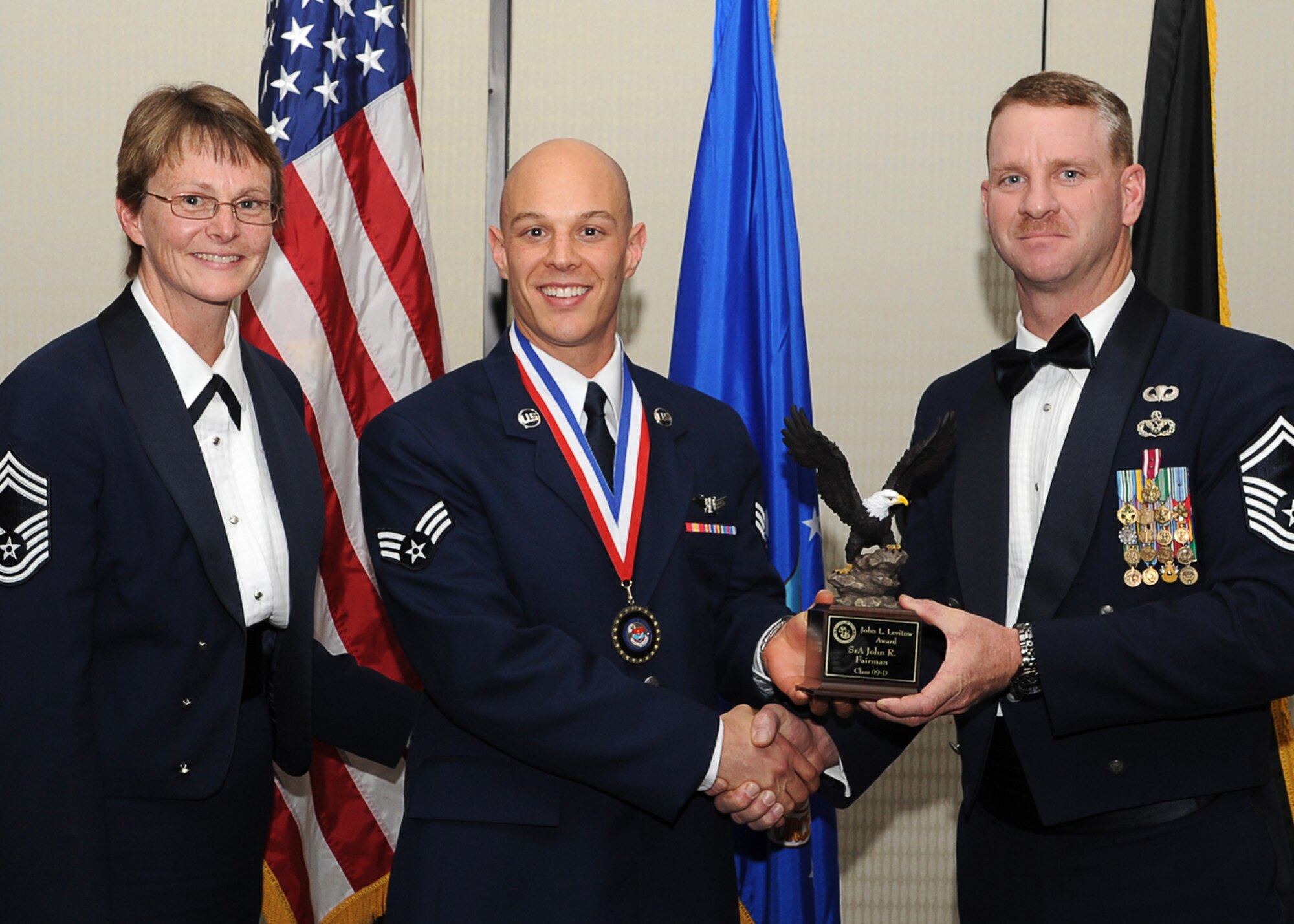AURORA, Colo. -- Senior Airman John Fairman, 460th Operations Support Squadron, seen here with Chief Master Sgt. Gerrie McCoy, 460th Medical Group Superintendent, receives his John L. Levitow Award from Senior Master Sgt. Dean Harris, 460th Civil Engineer Squadron Operations Superintendent.  The Airman Leadership School graduated 12 future Air Force leaders from the Doubletree hotel here March 27. (U.S. Air Force photo by Senior Airman Erika Brooke)