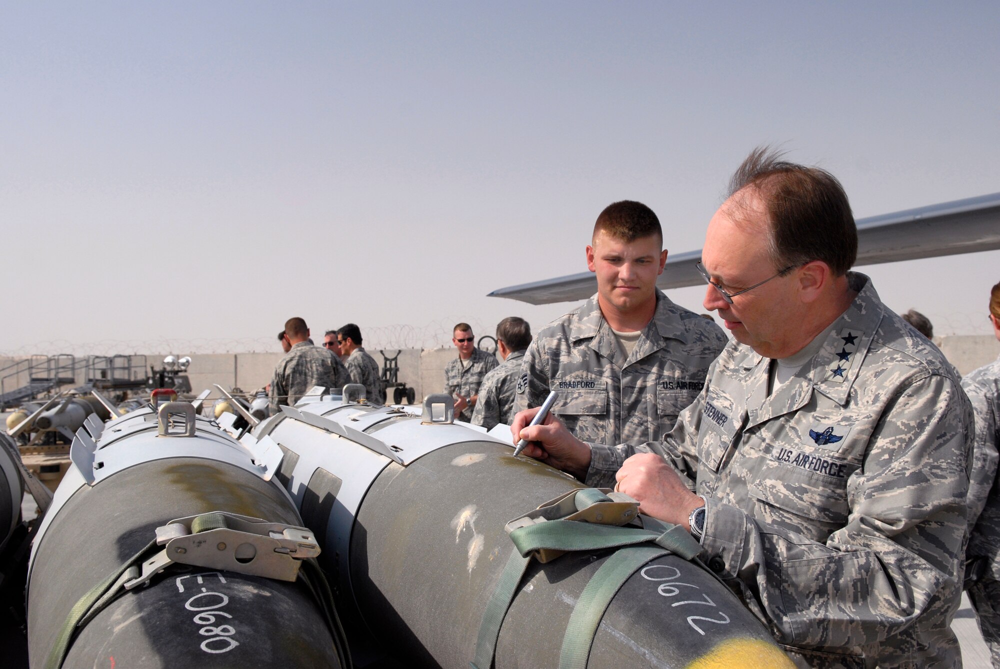Lt. Gen. Charles Stenner, commander of Air Force Reserve Command and chief of the Air Force Reserve, writes a message on a 2,000 lb guided bomb unit April 6 before it is loaded onto a B-1B Lancer at an air base in Southwest Asia for delivery to the enemy.  General Stenner is being briefed by Senior Airman Timothy Bradford, a maintainer from the 379th Expeditionary Maintenance Squadron. Airman Bradford, from Burleson, Texas, is deployed from Dyess Air Force Base, Texas. (U.S. Air Force photo/Senior Airman Andrew Satran)
