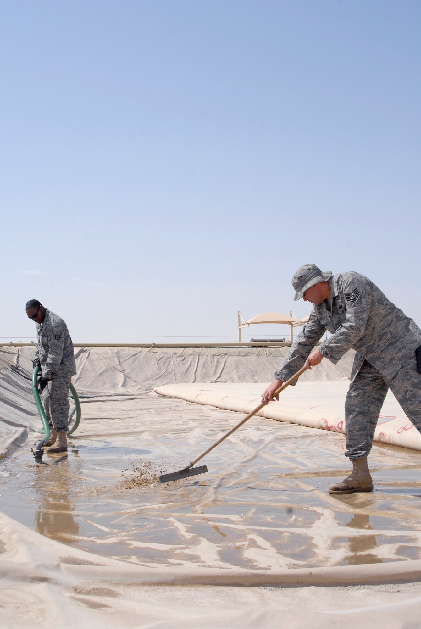 Staff Sgt. Carmarius Johnson, 379th Expeditionary Logistics Readiness Squadron (ELRS) bulk storage operator, and Tech. Sgt. John Neiffer, 379th ELRS NCO in charge of bulk expeditionary receiving transportation holding area (BERTHA), work together to remove water in one of the fuel holding areas as a part of preventative maintenance, Apr. 10, 2009, at an undisclosed location in Southwest Asia.  The fuel held in the BERTHA is distributed to various locations around the base where needed to ensure mission success.  Sergeant Johnson hails from Shreveport, La. and is deployed from Altus Air Force Base, Okla.  Sergeant Neiffer hails from Pottstown, Pa. and is deployed from Offutt Air Force Base, Neb.  Both are deployed in support of Operations Iraqi and Enduring Freedom and Combined Joint Task Force - Horn of Africa.  (U.S. Air Force photo/Senior Airman Andrew Satran/released)   