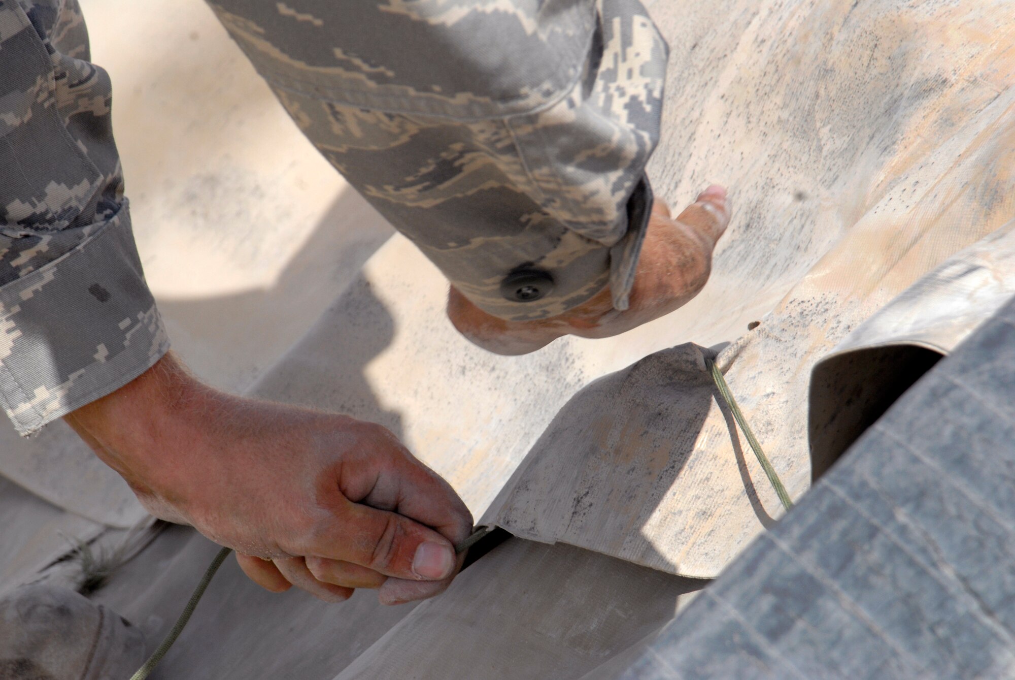 Tech. Sgt. Raymond Carpenter, 379th Expeditionary Logistics Readiness Squadron fuels bulk storage supervisor, ties and secures a berm liner down in the bulk expeditionary receiving transportation holding area (BERTHA), Apr. 10, 2009, at an undisclosed location in Southwest Asia.   The fuel held in the BERTHA is distributed to various locations around the base where needed to ensure mission success.  Sergeant Carpenter hails from Princeton, Idaho and is deployed from Ellsworth Air Force Base, S.D. in support of Operations Iraqi and Enduring Freedom and Combined Joint Task Force - Horn of Africa.  (U.S. Air Force photo/Senior Airman Andrew Satran/released)  