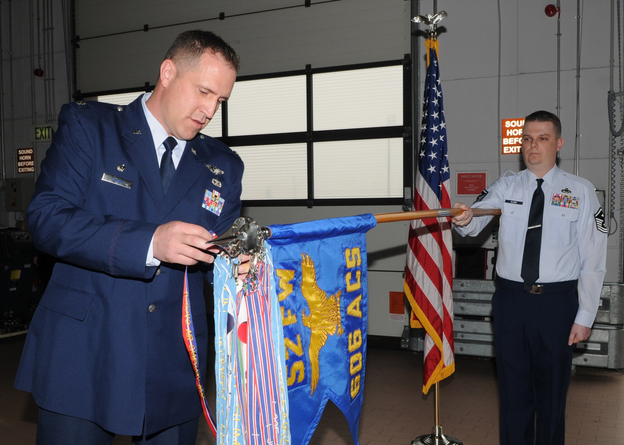 SPANGDAHLEM AB, Germany -- Lt. Col. Darren Ewing, 606th Air Control Squadron commander, attaches the Kosovo streamer to the guidon held by Master Sgt. Jeffrey Clark, 606th ACS 1st Sgt., during a ceremony April 13, 2009.  The Kosovo streamer was awarded to the 606 ACS for contributions during Operation Nobel Anvil.  (U.S. Air Force photo by Staff Sgt. Heather M. Norris)