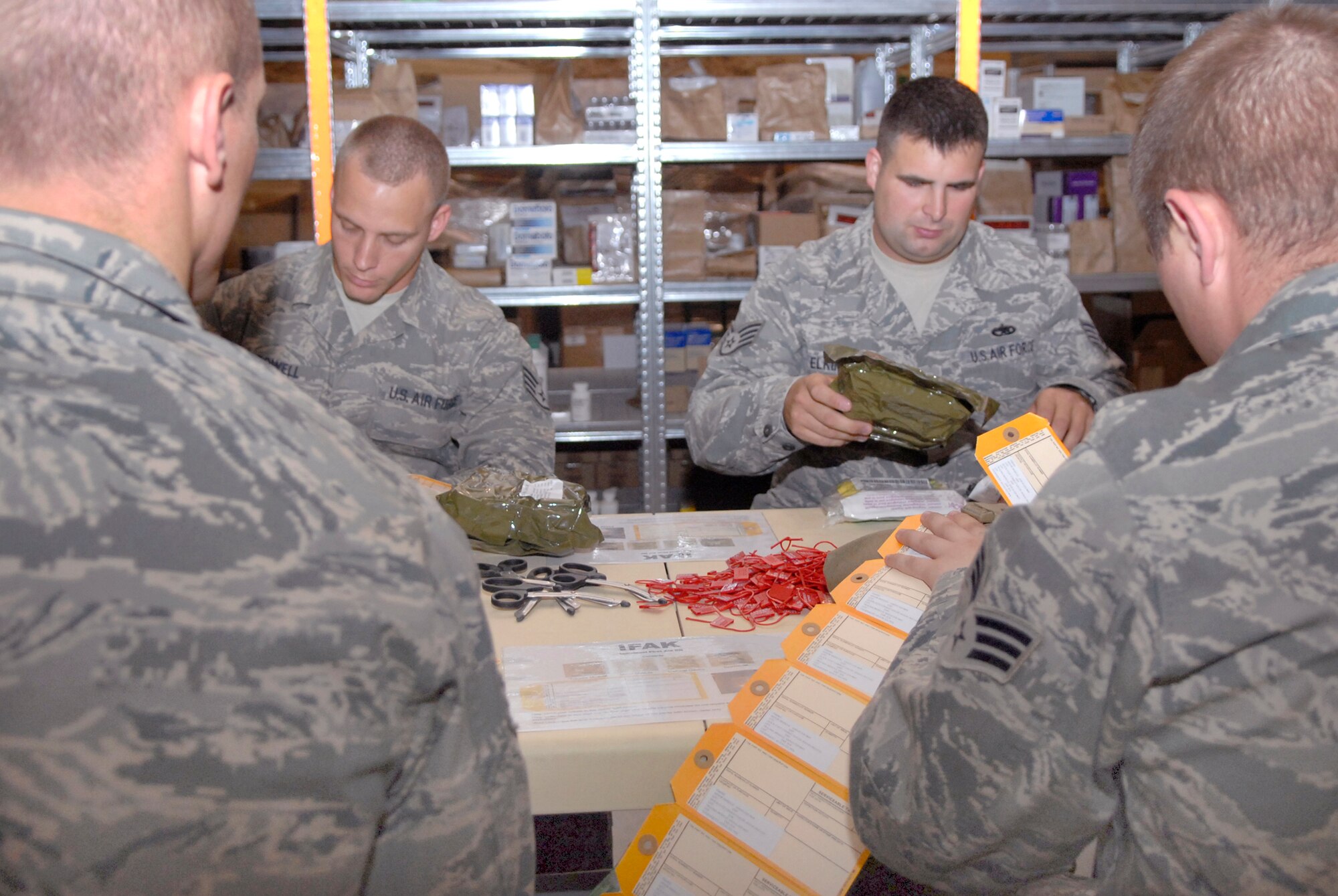 Senior Airman Nathaniel Hildreth, Staff Sgt. William Powell, Staff Sgt. Brandon Elkins, and Senior Airman Jonathan Bose, all from the 379th Expeditionary Communications Squadron, volunteer to help assemble Individual First Aid Kits here, Apr. 9, 2009, at an undisclosed location in Southwest Asia.  The volunteers put in the required items, checking for anything out of date to ensure the kits being distributed to personnel down range are effective.  Airman Hildreth hails from Cincinnati, Ohio and is deployed from Ramstein Air Base, Germany.  Sergeant Powell hails from Ridgeland, Miss. and is deployed from McCord Air Force Base, Wash.  Sergeant Elkins hails from Norwalk, Wis. and is deployed from Tyndall Air Force Base, Fla.  Airman Bose hails from Terre Haute, Ind. and is deployed from the 181st Intelligence Air National Guard Wing, Hulman Field, Ind.  All are deployed in support of Operations Iraqi and Enduring Freedom and Combined Joint Task Force - Horn of Africa.  (U.S. Air Force photo/Senior Airman Andrew Satran/released)