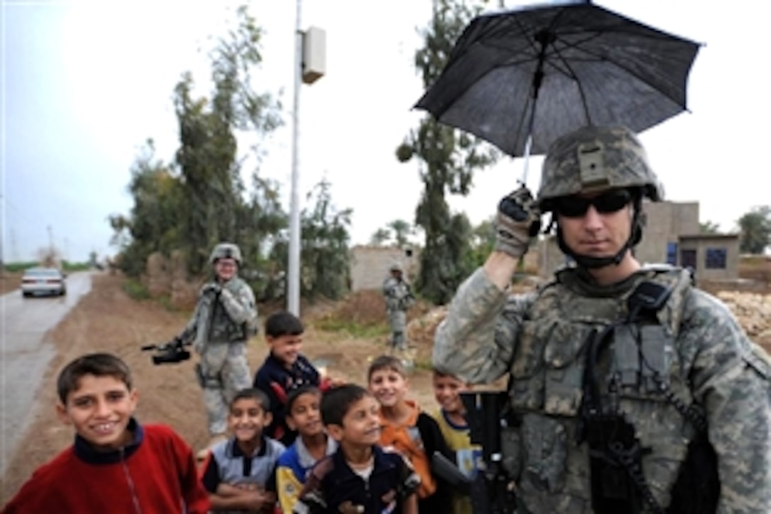 U.S. Army Staff Sgt. Joshua Hedetniemi tests out the tactical capabilities of his new Iraqi friend’s umbrella while on a patrol to Nadeem Village, Iraq, April 9, 2009. The soldiers are assigned to Company A, 1st Battalion, 111th Infantry Regiment, 56th Stryker Brigade Combat Team, 28th Infantry Division, Pennsylvania National Guard, Multi-National Division-Baghdad.