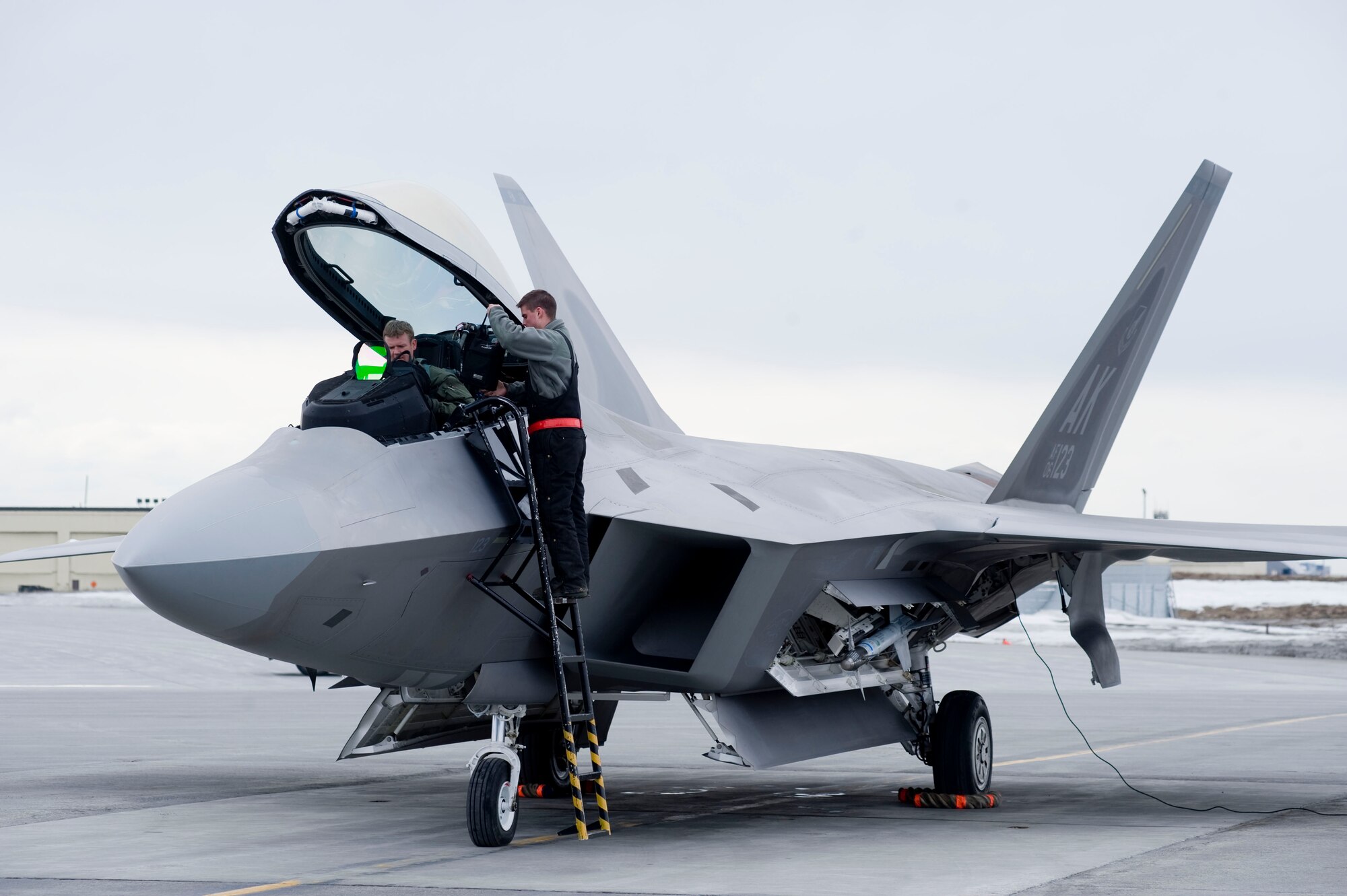 ELMENDORF AIR FORCE BASE, Alaska-- Airman 1st Class Mathew Bales hands over Capt. Ryan Pelkola gear to him April 14, 2009. Capt. Pelkola from the 525th Fighter Squadron will be dropping one of the first JDAM dropped by 525th FS. (U.S. Air Force photo by Senior Airman Jonathan Steffen)