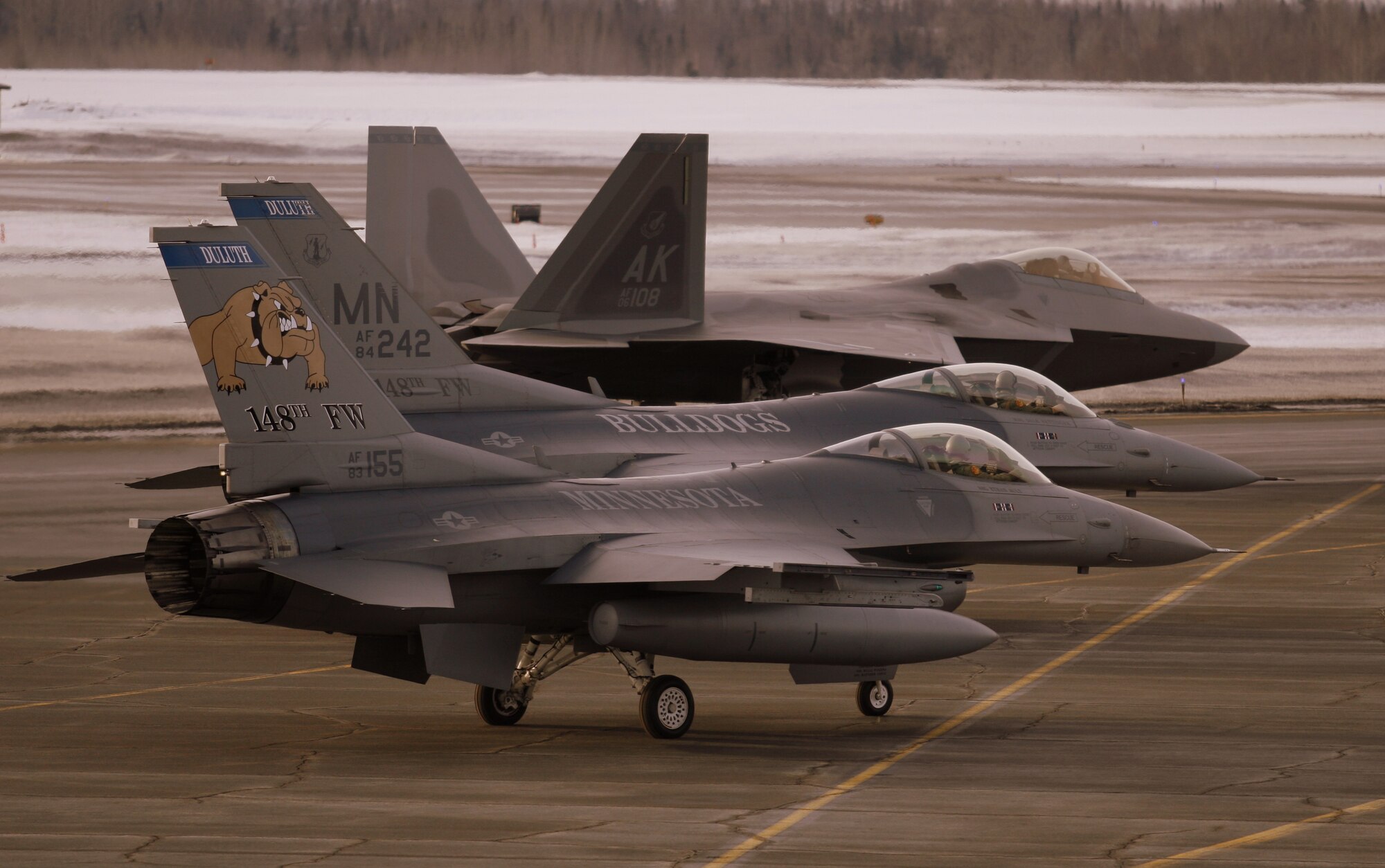Two F-16C Fighting Falcons of the 148th Fighter Wing, Duluth, Minn. prepare for take off next to an F22 Raptor on March 3rd, 2008 during a recent deployment to Elmendorf AFB, Alaska.  While deployed, the 148th was the first non-Alaskan or Canadian unit to support Alaska Command (ANR) alert and the first F-16 unit to intercept Russian bombers, also knows as "Bears". (U.S. Air Force photo by Lt. Col. Kevin Peterson)  (Released)