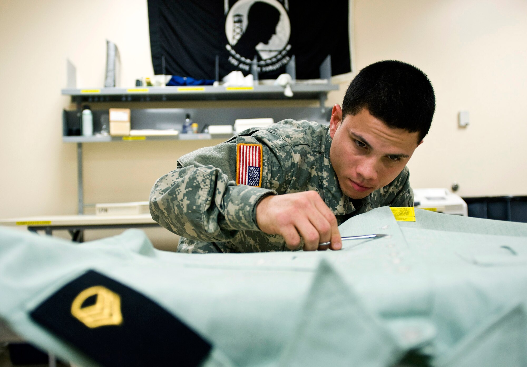 Specialist Xavier Gonzalez, a mortuary affairs specialist, prepares a U.S. Army service dress shirt for a fallen solider March 31. Servicemembers working in the uniform section of the Air Force Mortuary Affairs Operations Center at Dover Air Force Base, Del., prepare uniforms for the fallen heroes and work with military escorts for the dignified-transfer-of-remains process.  Specialist Gonzalez is deployed from the Army Reserve, 311th Quartermaster Company in Puerto Rico.  (U.S. Air Force photo/Staff Sgt. Bennie J. Davis III)