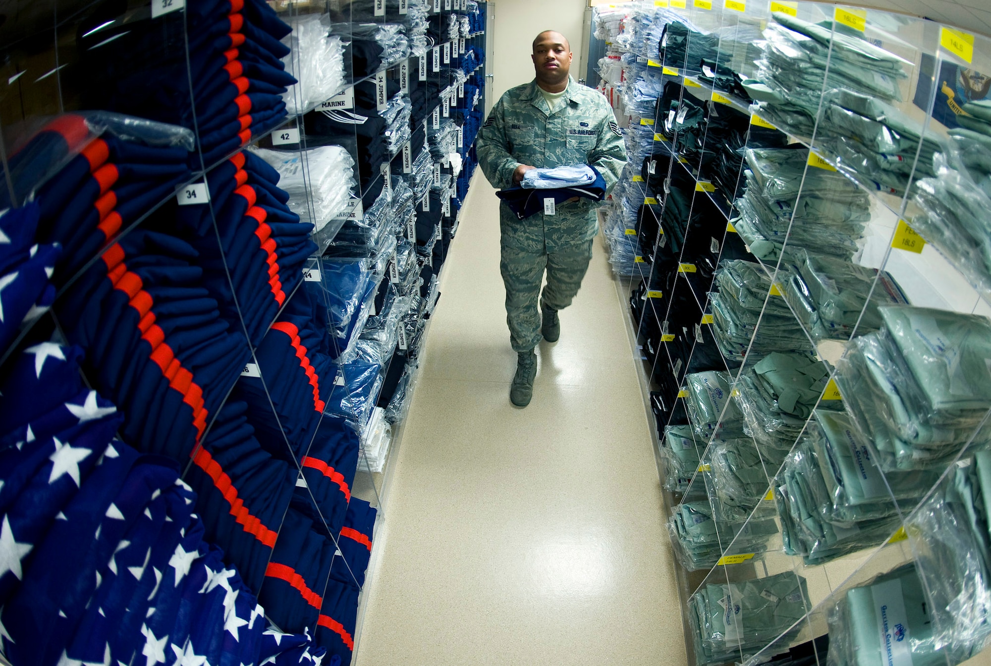 Staff Sgt. Charles Bell, a mortuary technician at the Air Force Mortuary Affairs Operations Center at Dover Air Force Base, Del., walks through rows of military service dress uniforms that are stored there for every rank and size. Sgt. Bell is the Air Force non-commisioned officer in charge of logistics and oversees ordering and stocking service dress uniforms and items for dignified transfer of remains.  (U.S. Air Force photo/Staff Sgt. Bennie J. Davis III)
