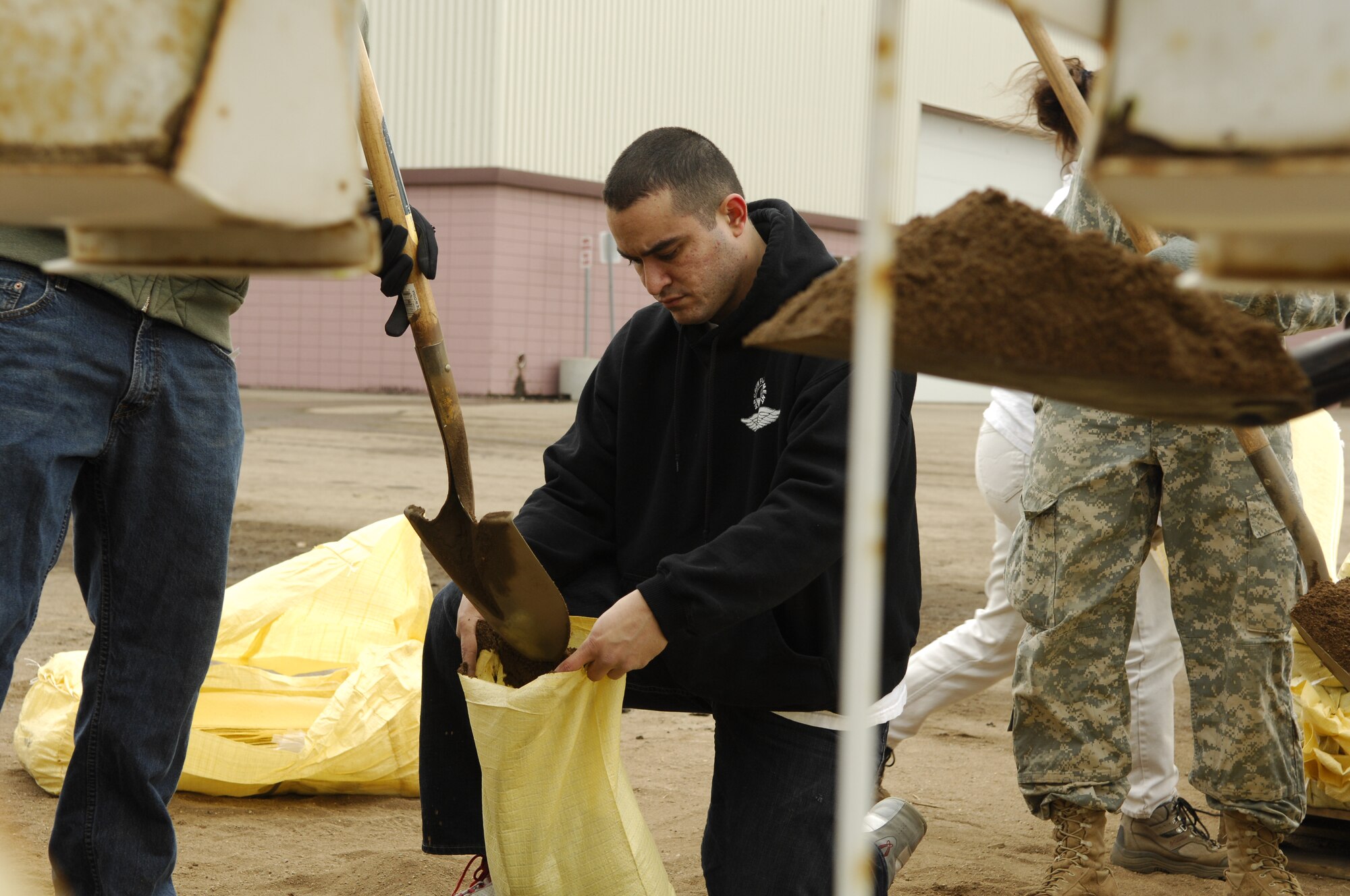 MINOT, N.D. -- Airman Ryan C. Reyes, 5th Operations Support Squadron aircrew flight equipment apprentice, holds a sandbag while a fellow volunteer fills it outside the All Seasons Arena here April 10. Airman Reyes worked alongside other 5th OSS volunteers, Army National Guard and civilians filling sandbags in preparation of flood relief efforts. (U.S. Air Force photo by Staff Sgt. Thomas Dow)