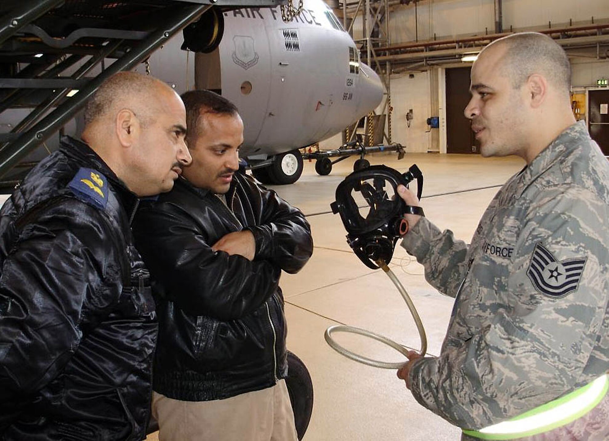 Tech. Sgt. Ruben Rodriguez talks about the air mask he uses when going inside the fuel tanks of a C-130 Hercules to the Iraqi air force flight surgeons Major (Dr.) Abdulrazzaq and Lt. (Dr.) Hazem March 13 at Ramstein Air Base, Germany. Sergeant Rodriguez is assigned to the 86th Maintenance Squadron. (Courtesy photo) 
