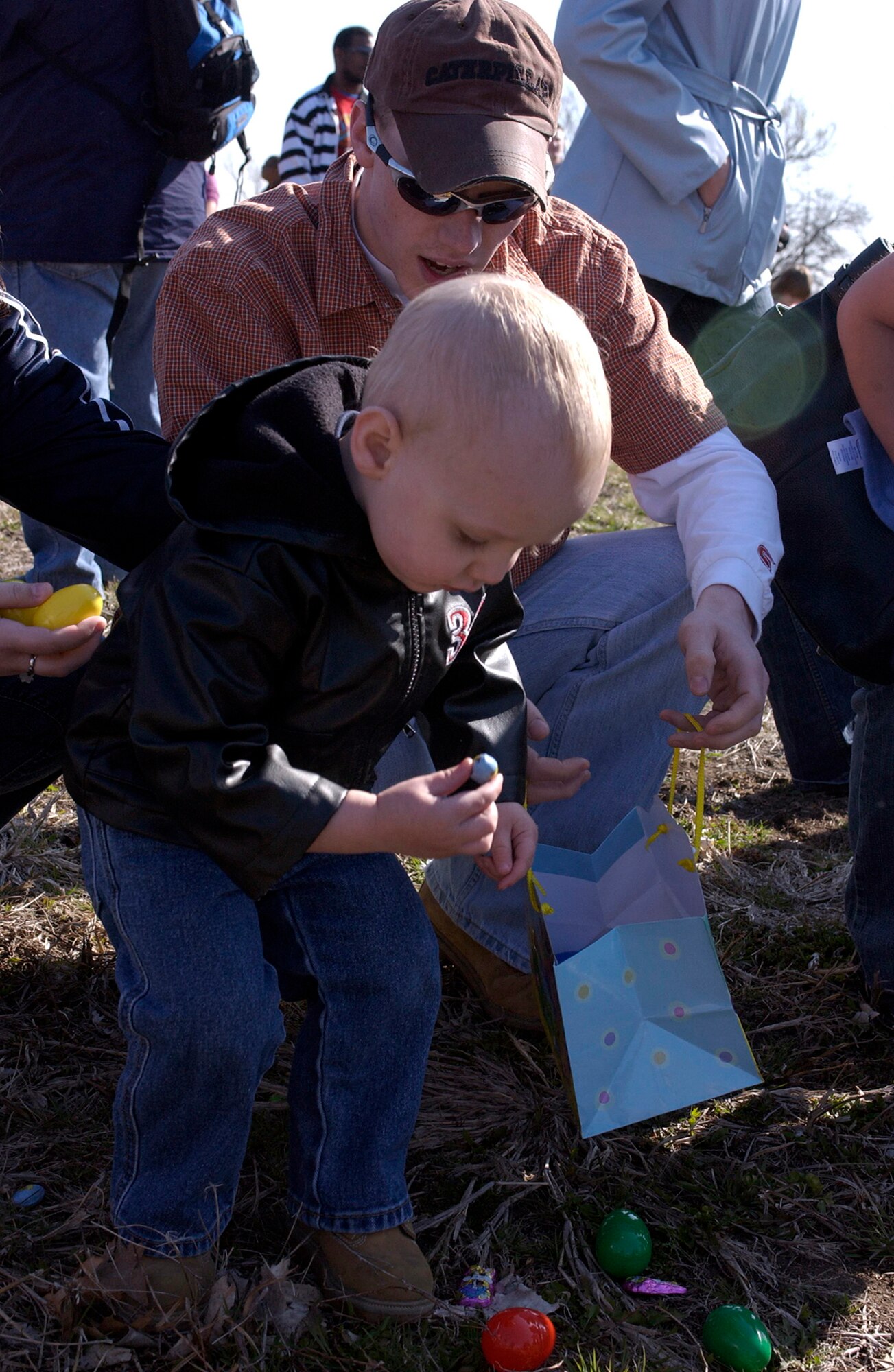 OFFUTT AIR FORCE BASE, Neb. -- Craig Sheasley Jr. grabs a piece of candy for his Easter bag as father Senior Airman Craig Sheasley, 55th Force Support Squadron, encourages him during Offutt's annual Easter Egg Scramble at the base lake April 11. More than 500 Easter egg hunters were in attendance for the event which broke the children and adults into five groups and allowed them to "scramble" for eggs, toys and candy.  U.S. Air Force Photo By: Staff Sgt. Richard Williams