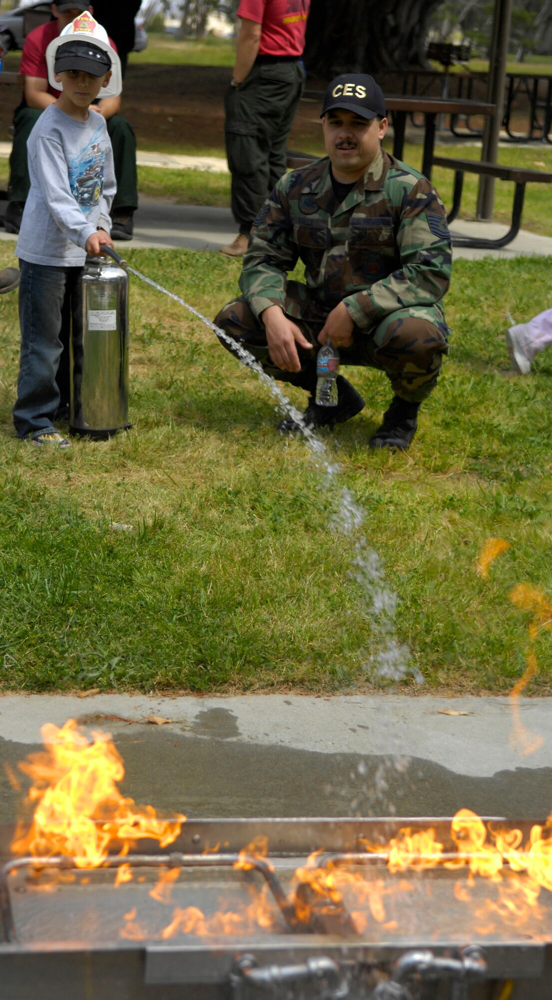 VANDENBERG AIR FORCE BASE, Calif. -- Learning to "Pull, Aim, Squeeze and Shoot," Zak Doyle gets some hands-on training with a fire extinguisher from Tech Sgt. Juan Valle April 10 during Fire Safety Day here. Sergeant Valle and other members of the  30th Civil Engineer Squadron's fire department took time to teach children the importance of fire safety during the event. (U.S. Air Force photo/Airman 1st Class Andrew Lee) 