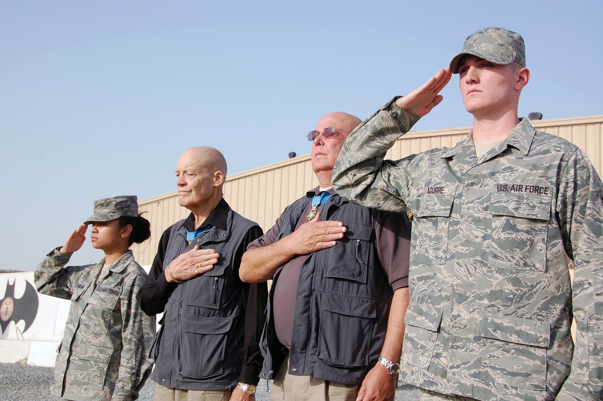Medal of Honor recipients retired Army Col. Robert Howard and retired Army Command Sgt. Maj. Gary Littrell are flanked by Airmen 1st Class Alyssa Aguilar and Matthew Aguirre as they render honors to the flag during a retreat ceremony April 10 at an air base in Southwest Asia. Colonel Howard and Sergeant Major Littrell visited with members of the 386th Air Expeditionary Wing during a Medal of Honor Society tour of the U.S. Air Forces Central area of responsibility. Airmen Aguilar and Aguirre are assigned to the 386th Expeditionary Medical Group. (U.S. Air Force photo/Staff Sgt. Thomas J. Doscher) 
