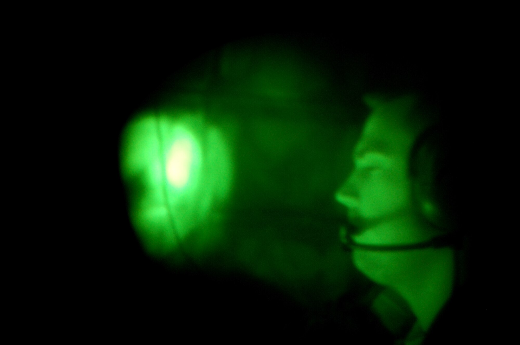 Through the lens of night vision goggles, Staff Sgt. Kenneth Essick, boom operator for the 2nd Air Refueling Squadron on McGuire Air Force Base, N.J., refuels a plane from the boom pod of a KC-10 Extender on April 9, 2009, during an air refueling mission.  On that mission, Sergeant Essick refueled his father's E-8C Joint Surveillance Target Attack Radar System aircraft from the 116th Air Control Wing of Robins AFB, Ga.  His father, Chief Master Sgt. Randal Money, was on his final flight as a flight engineer for the E-8C.  (U.S. Air Force Photo/Tech. Sgt. Scott T. Sturkol)