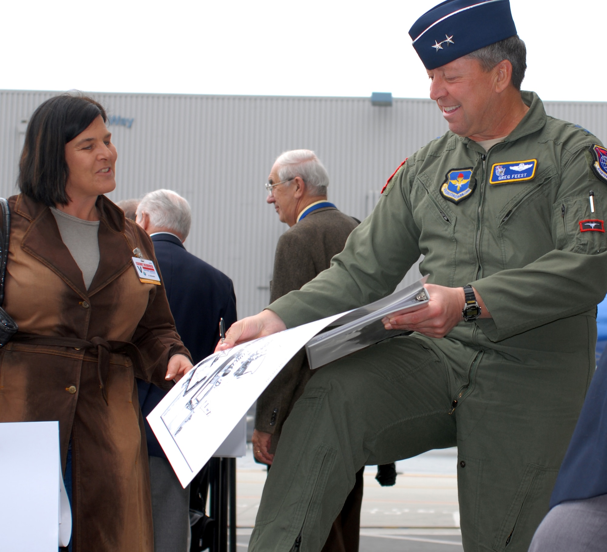 Maj. Gen. Greg Feest, 19th Air Force commander at Randolph Air Force Base, Texas, hands a lithograph he signed to an attendee at the conclusion of a ceremony honoring the T-38 Talon’s first flight April 10 at the Northrop Grumman facility in El Segundo, Calif. (U.S. Air Force photo by Michael Briggs)