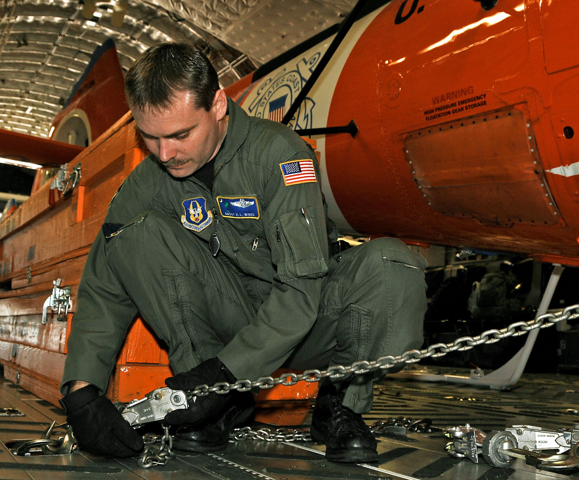 Senior Master Sgt. H. L. Wiggs helps secure a Coast Guard helicopter aboard a C-17 Globemaster III April 7 at Charleston Air Force Base, S.C. The helicopters were delivered to Central America for missions there. Sergeant Wiggs is a reservist with the 701st Airlift Squadron. (U.S. Air Force photo/Capt. Chett Collier) 
