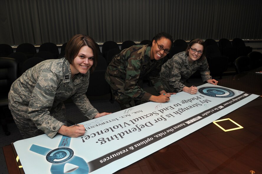 From left to right, Capt. Vanessa Vanden Bout, Kaiserslautern Military Community Sexual Assault Response Coordinator; Capt. Shontre McFarlin, Kaiserslautern Military Community Sexual Assault Response Coordinator chief; and 1st Lt. Kelly Barton, Kaiserslautern Military Community Sexual Assault Response Coordinator, sign the SARC banner April 1 at Ramstein Air Base, pledging to help raise awareness for the month. (U.S. Air Force photo by Airman 1st Class Grovert Fuentes-Contreras)