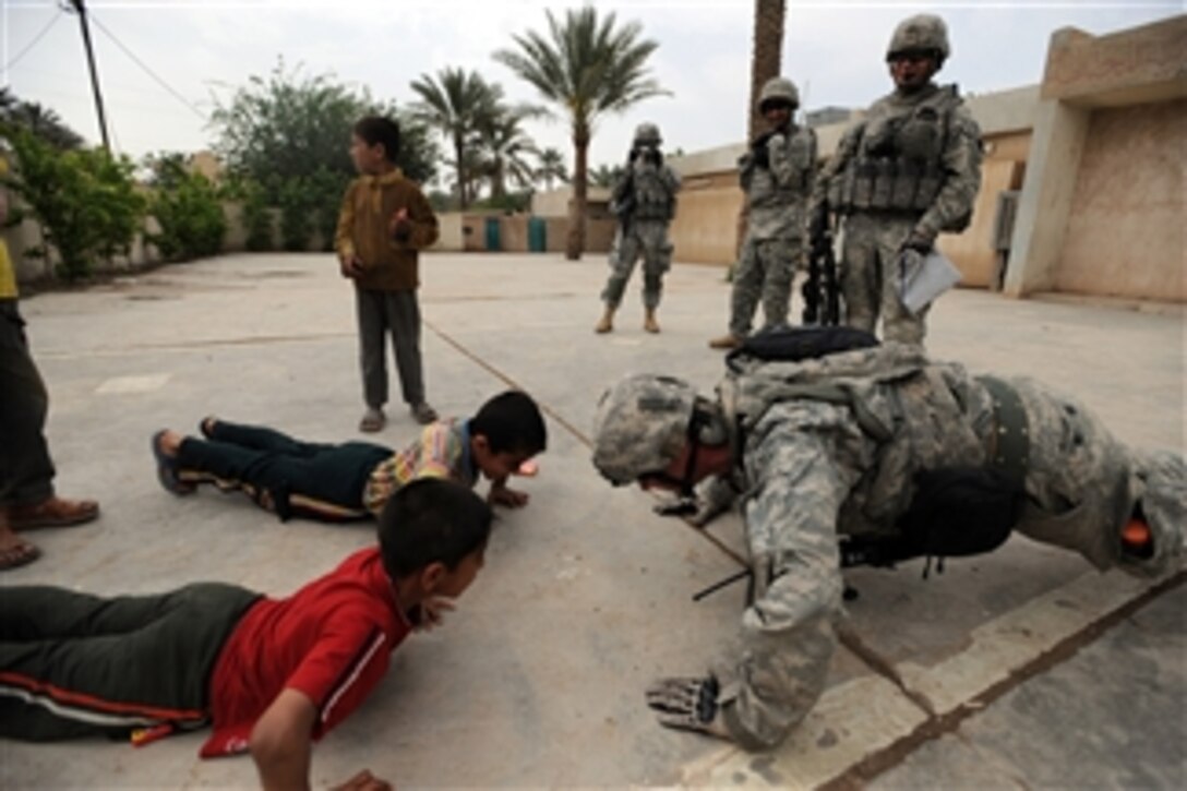 U.S. Army Staff Sgt. Josh Hedetniemi does pushups to amuse Iraqi children outside a school near Sheik Hammad, Iraq, on April 8, 2009.  Hedetniemi is from Alpha Company, 1st Battalion, 111th Infantry Regiment, 56th Stryker Brigade Combat Team, 28th Infantry Division.  