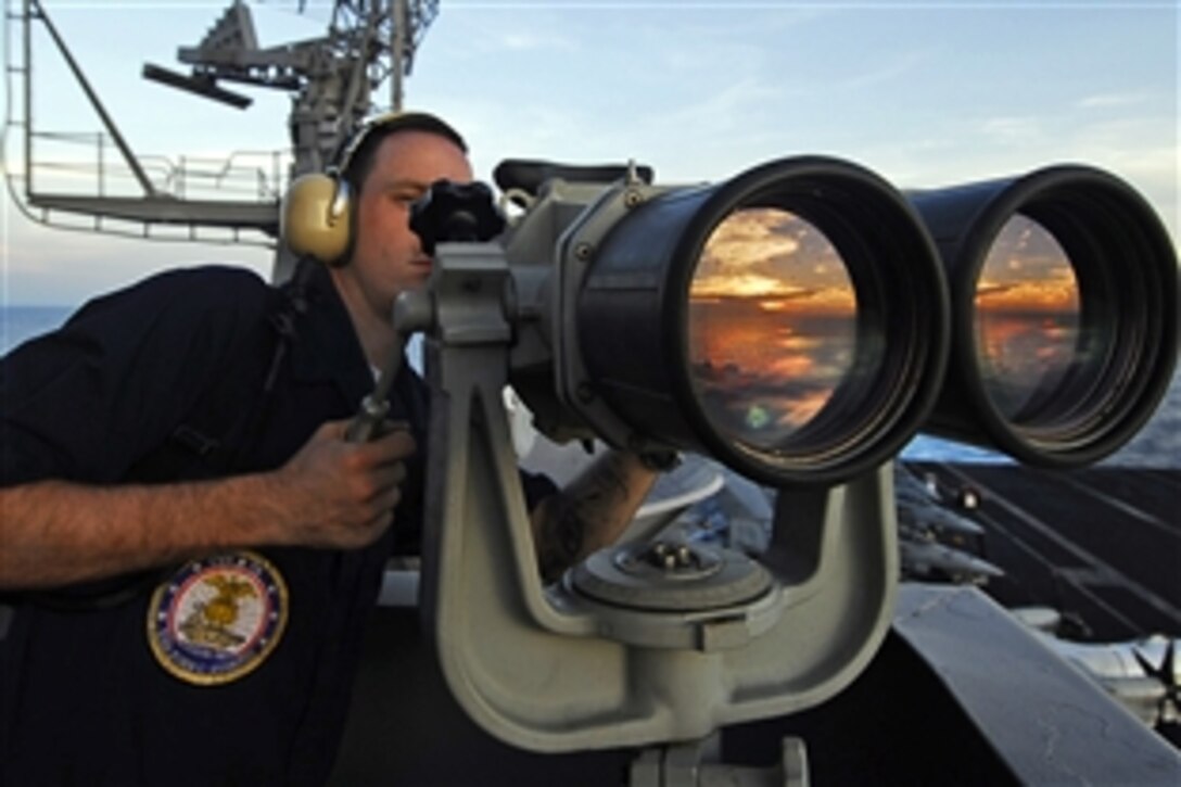 U.S. Navy Seaman Apprentice Paul Coombs uses the "big eyes" to locate surface contacts while standing port forward lookout watch on the island structure aboard the aircraft carrier USS John C. Stennis, Pacific Ocean, April 8, 2009. The USS John C. Stennis is on a scheduled six-month deployment to the western Pacific Ocean.